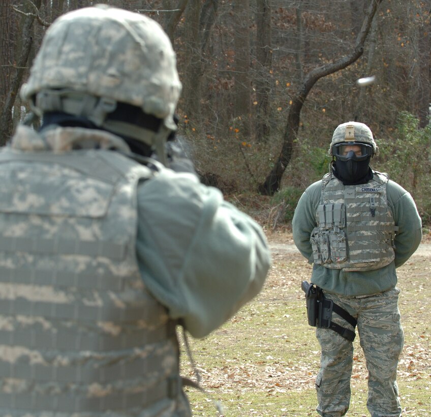LANGLEY AIR FORCE BASE, Va. -- Tech. Sgt. Matthew Loiselle, 633d Security Forces Squadron, fires a Beretta 9 mm pistol equipped with Ultimate Training Munitions ammunition at Airman Juan Cardenas, also from the 633 SFS, during UTM ballistics training at Bethel Park Feb. 3 UTM allows trainees to experience the physiological effects of being fired upon without the lethality of conventional ammunition. (U.S. Air Force photo/Airman 1st Class Jason J. Brown) (RELEASED)