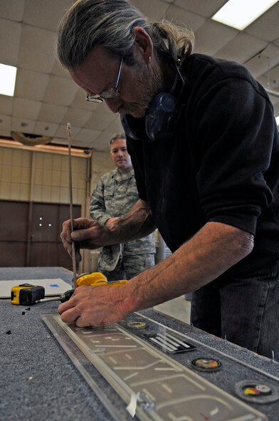 Mike Jarrett, 2nd Force Support Squadron wood crafts center manager, fixes a gift for Master Sgt. Marcus Cooper, 2nd Maintenance Operations Squadron first sergeant, Feb. 8 at Barksdale Air Force Base, La. Mr. Jarrett builds retirement and going-away gifts, trophy cases, recognition boards, podiums, conference tables and much more. "I can pretty much build anything a customer needs as long as it is made of wood," he said. Anyone who needs assistance with a project can receive help from Mr. Jarrett. The wood crafts center also has classes to teach others how to use the wood-working tools. For more information, call 456-3409. (U.S. Air Force photo/Staff Sgt. John Gordinier)(released)