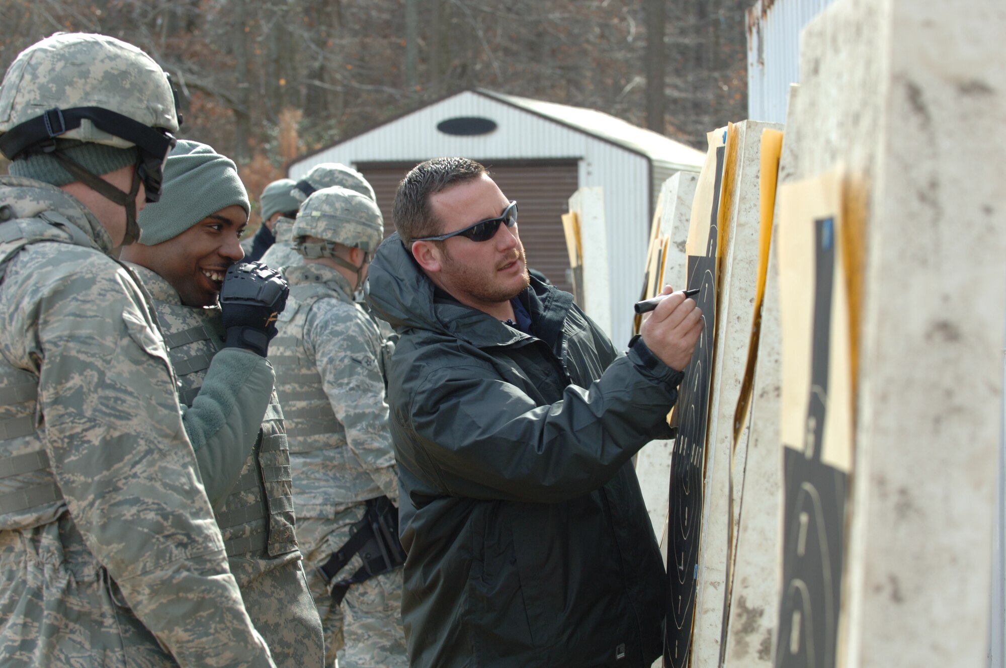 LANGLEY AIR FORCE BASE, Va. -- Airmen from the 633d Security Forces Squadron watch as Eric Seto, Ultimate Training Munitions training manager, marks impact points on target sheets during UTM ballistics training at Bethel Park Feb. 3. Unlike conventional ammunition, UTM rounds utilize non-lethal dye marker projectiles suitable for force-on-force use. (U.S. Air Force photo/Airman 1st Class Jason J. Brown) (RELEASED)