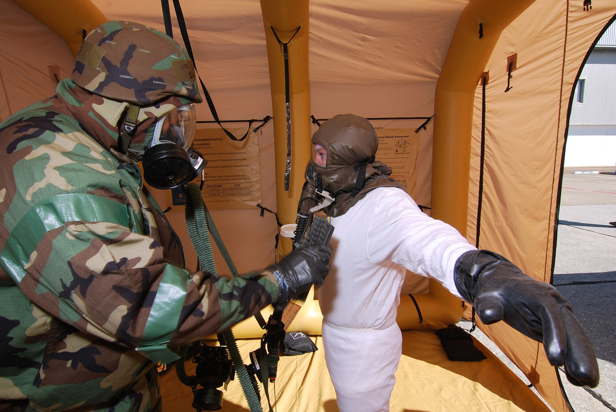 Staff Sgt. Demetrius Brown, an Aircrew Flight Equipment technician, simulates using a chemical detection device on 1st Lt. Patrick Croasdale, a pilot with the 700th Airlift Squadron, during one of the final steps in the decontamination training, Feb 6.  A lucky couple of airmen get to dress out and go through the stations as the rest of the class observes for the refamiliarization training.  The training takes them from start to finish through an Air Force decontamination line and provides good insight as to what to they will experience in the process.  (U.S.  Air Force photo/ Brad Fallin)
