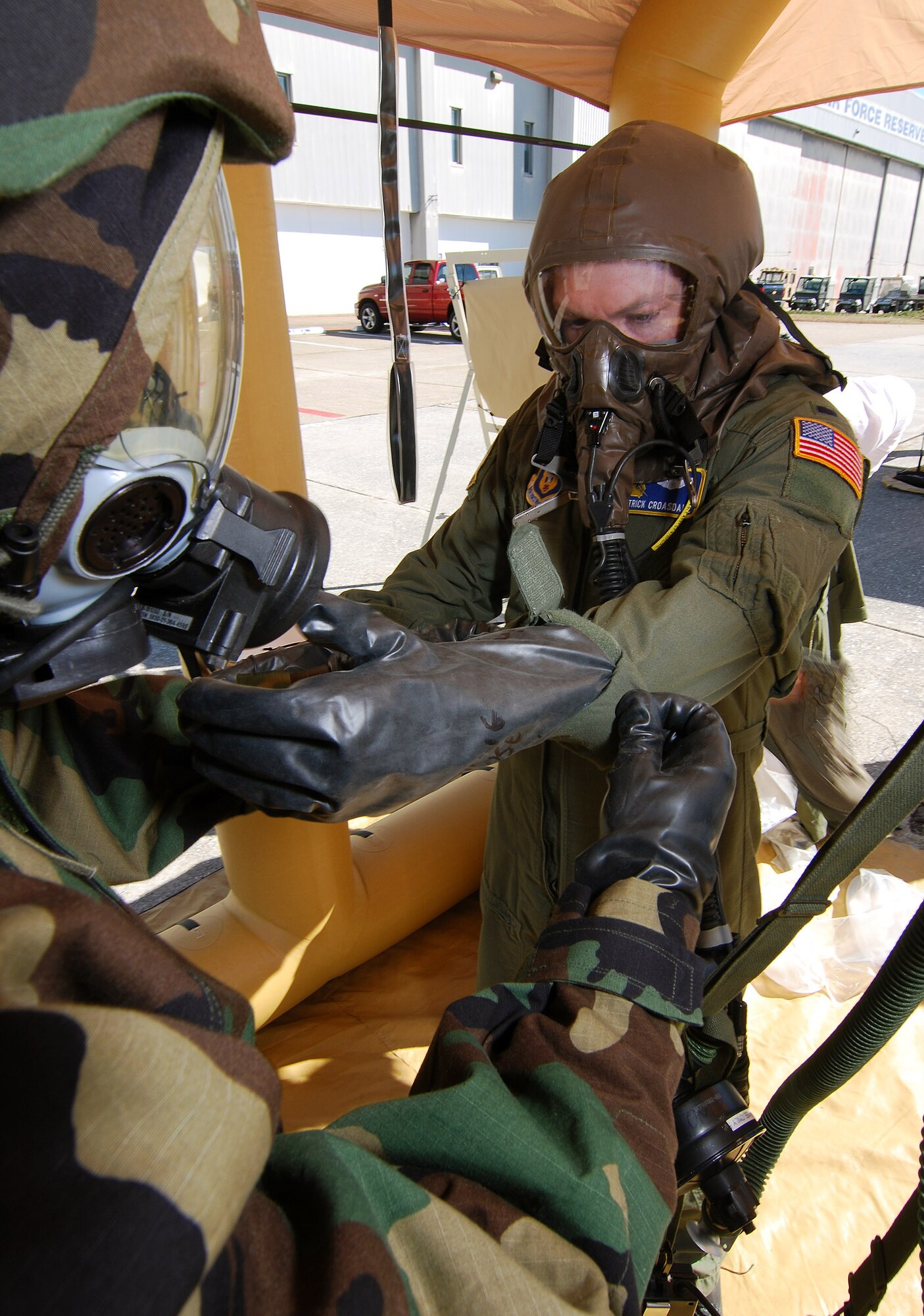 Tech Sgt. Preston Caldwell, an Aircrew Flight Equipment technician, rolls back the flight suit sleeve of 1st Lt. Patrick Croasdale, a pilot with the 700th Airlift Squadron, during decontamination training, Feb 6.  A lucky couple of airmen get to dress out and go through the stations as the rest of the class observes for the refamiliarization training.  The training takes them from start to finish through an Air Force decontamination line and provides good insight as to what to they will experience in the process.  (U.S.  Air Force photo/ Brad Fallin)