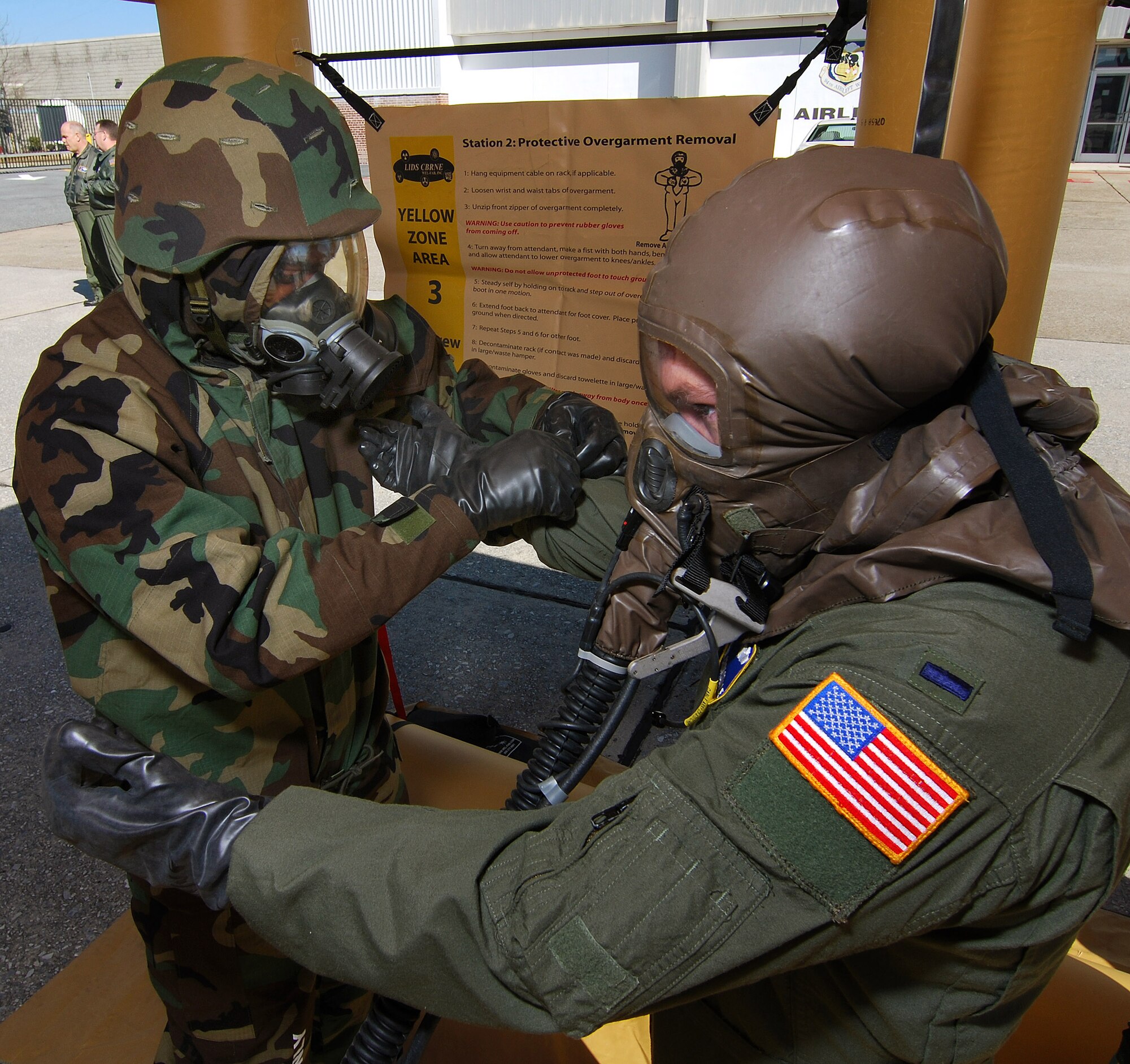 Tech Sgt. Preston Caldwell, an Aircrew Flight Equipment technician, rolls back the flight suit sleeve of 1st Lt. Patrick Croasdale, a pilot with the 700th Airlift Squadron, during decontamination training, Feb 6.  A lucky couple of airmen get to dress out and go through the stations as the rest of the class observes for the refamiliarization training.  The training takes them from start to finish through an Air Force decontamination line and provides good insight as to what to they will experience in the process.  (U.S.  Air Force photo/ Brad Fallin)