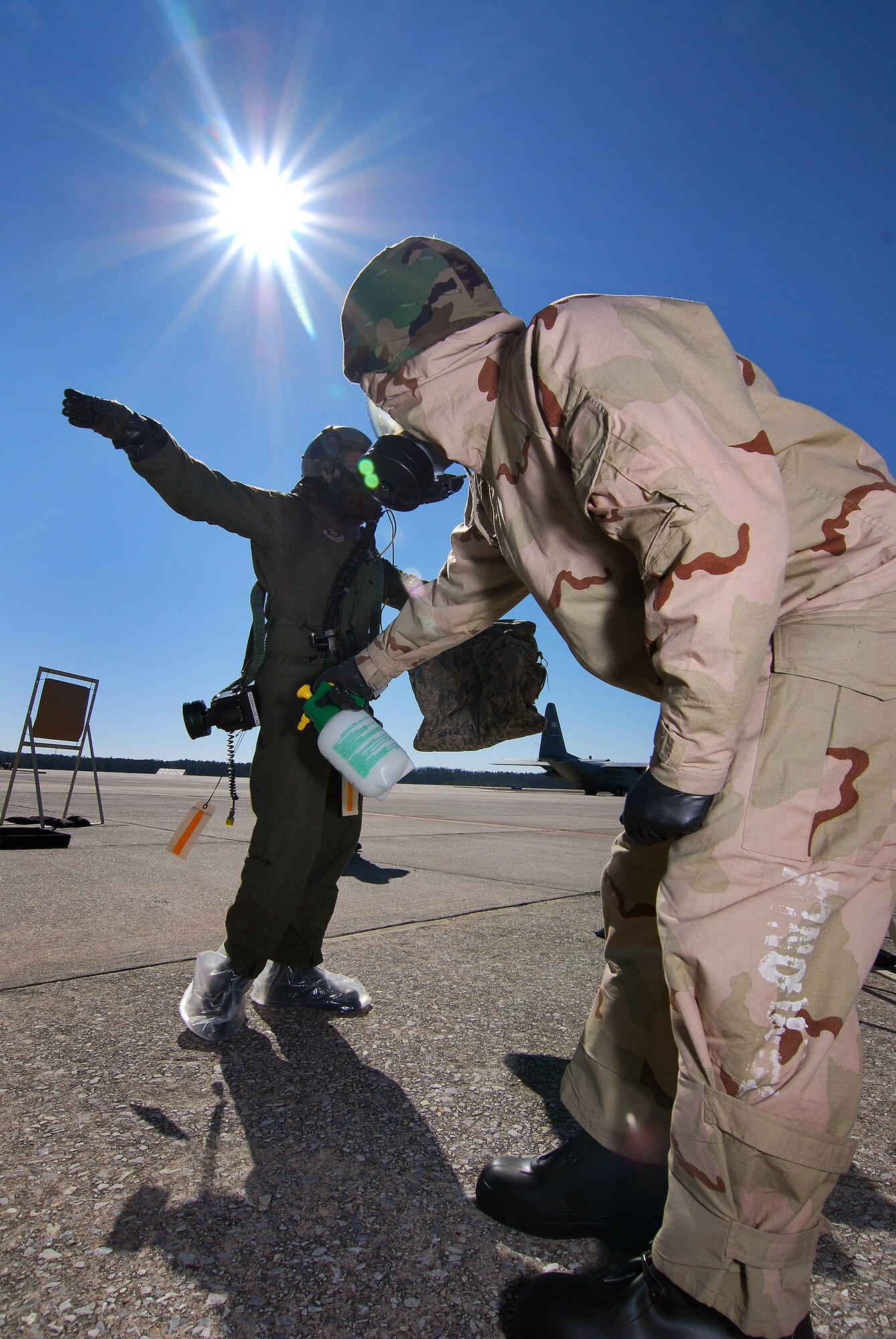 Tech Sgt. Lance Wilson, an Aircrew Flight Equipment technician, simulates spraying a neutralizing agent on 1st Lt. Seth King, a pilot with the 700th Airlift Squadron, during decontamination training, Feb 6.  A lucky couple of airmen get to dress out and go through the stations as the rest of the class observes for the refamiliarization training.  The training takes them from start to finish through an Air Force decontamination line and provides good insight as to what to they will experience in the process.  (U.S.  Air Force photo/ Brad Fallin)