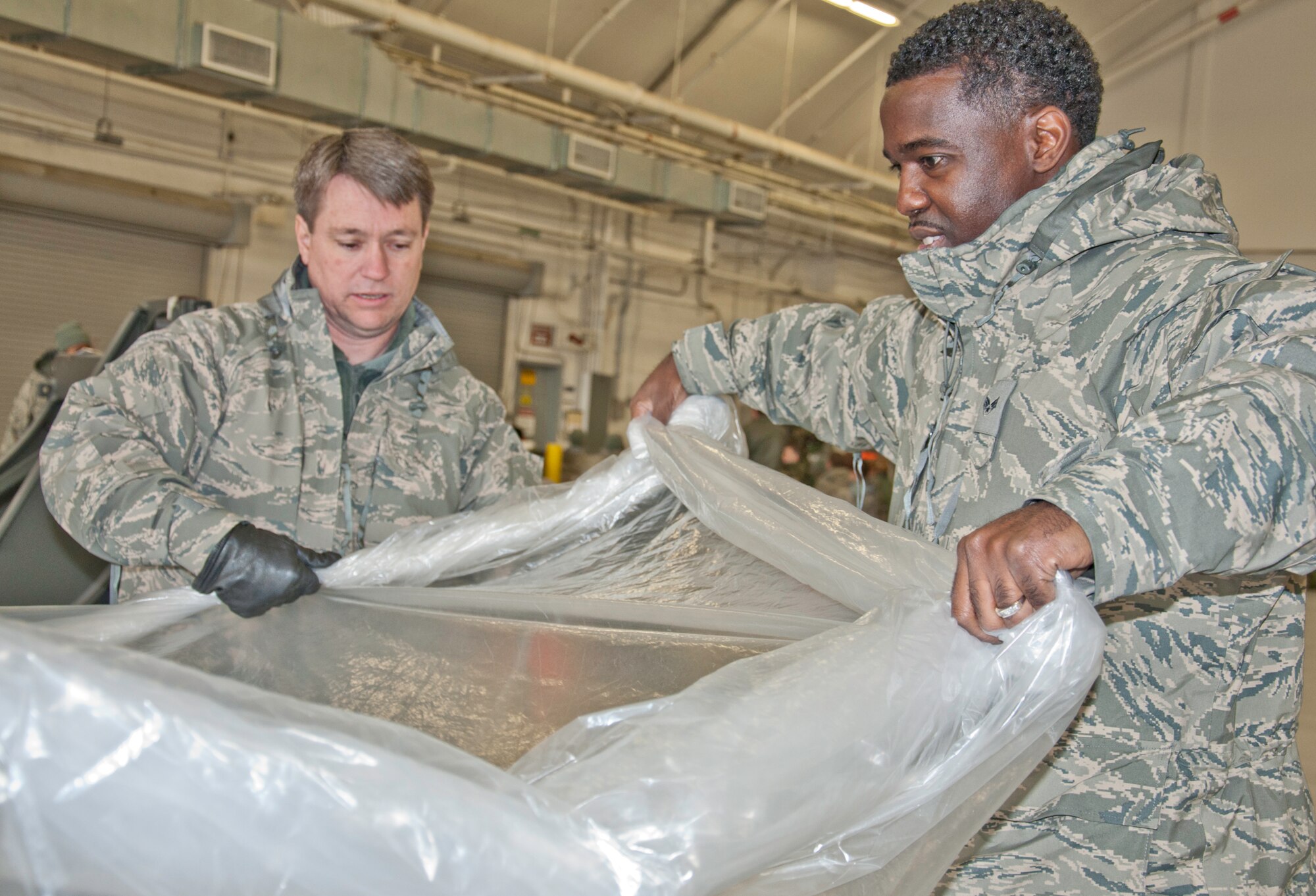 JOINT BASE ANDREWS, Md. -- Tech. Sgt. Steven Hensley (left), 459th Communications Flight knowledge operations specialist, and Senior Airman Joseph Taylor, 459th Air Refueling wing financial management specialist, learn how to protect equipment from chemical contamination during readiness and Ability to Survive and Operate training here Feb. 4. The 459 ARW attended 14 different readiness and ATSO courses over a two-day period that were focused on preparing them for exercises and an upcoming Operational Readiness Inspection. (U.S. Air Force photo/Staff Sgt. Sophia Piellusch)