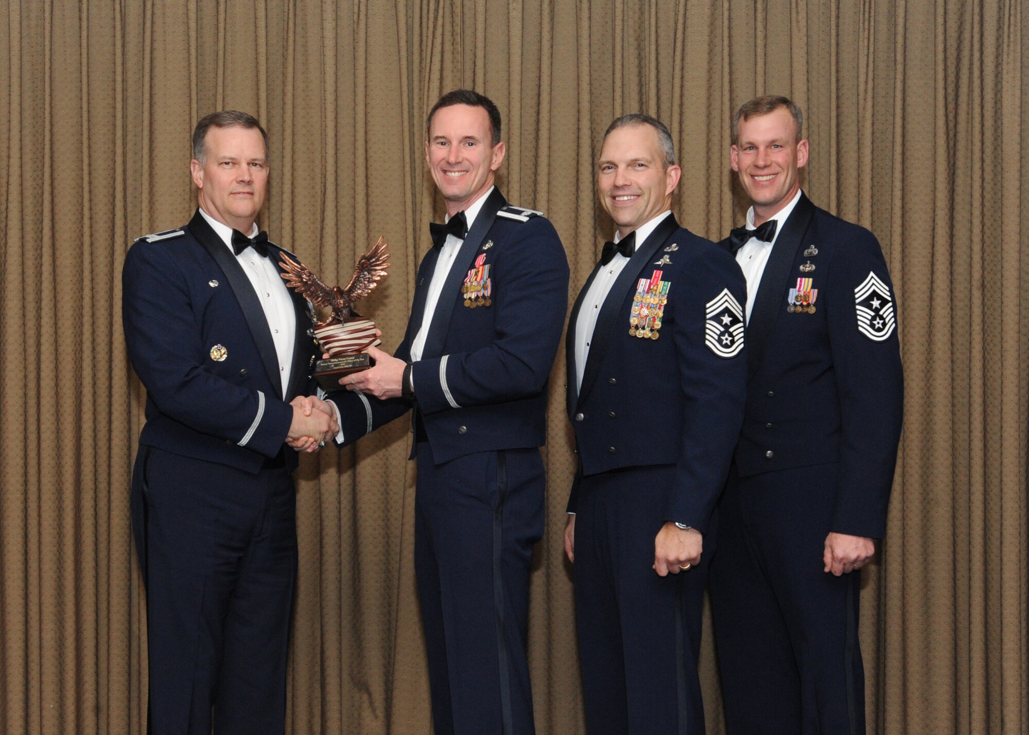 Lt. Col. Mark Zimmerhanzel, 319th Civil Engineering Squadron commander, accepts the 2010 Senior Non-commissioned Officer of the Year award on behalf of recipient Senior Master Sgt. Victor Correa, 319th Civil Engineering Squadron, for Grand Forks Air Force Base Feb. 4 at the Northern Lights Club. Presenting the award is Col. Don Shaffer, 319th Air Refueling Wing commander, along with Command Chief Master Sgt. Martin Klukas, Air Combat Command, and Command Chief Master Sgt. David Carlson, 319th Air Refueling Wing. (U.S. Air Force photo by Staff Sgt. Suellyn Nuckolls)