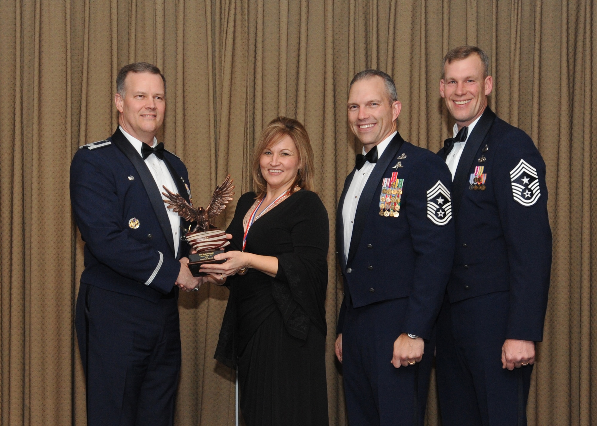 Mrs. Sonja Gonzalez is presented with the 2010 Spouse of the Year award for Grand Forks Air Force Base Feb. 4 at the Northern Lights Club. Presenting the award is Col. Don Shaffer, 319th Air Refueling Wing commander, along with Command Chief Master Sgt. Martin Klukas, Air Combat Command, and Command Chief Master Sgt. David Carlson, 319th Air Refueling Wing. (U.S. Air Force photo by Staff Sgt. Suellyn Nuckolls)