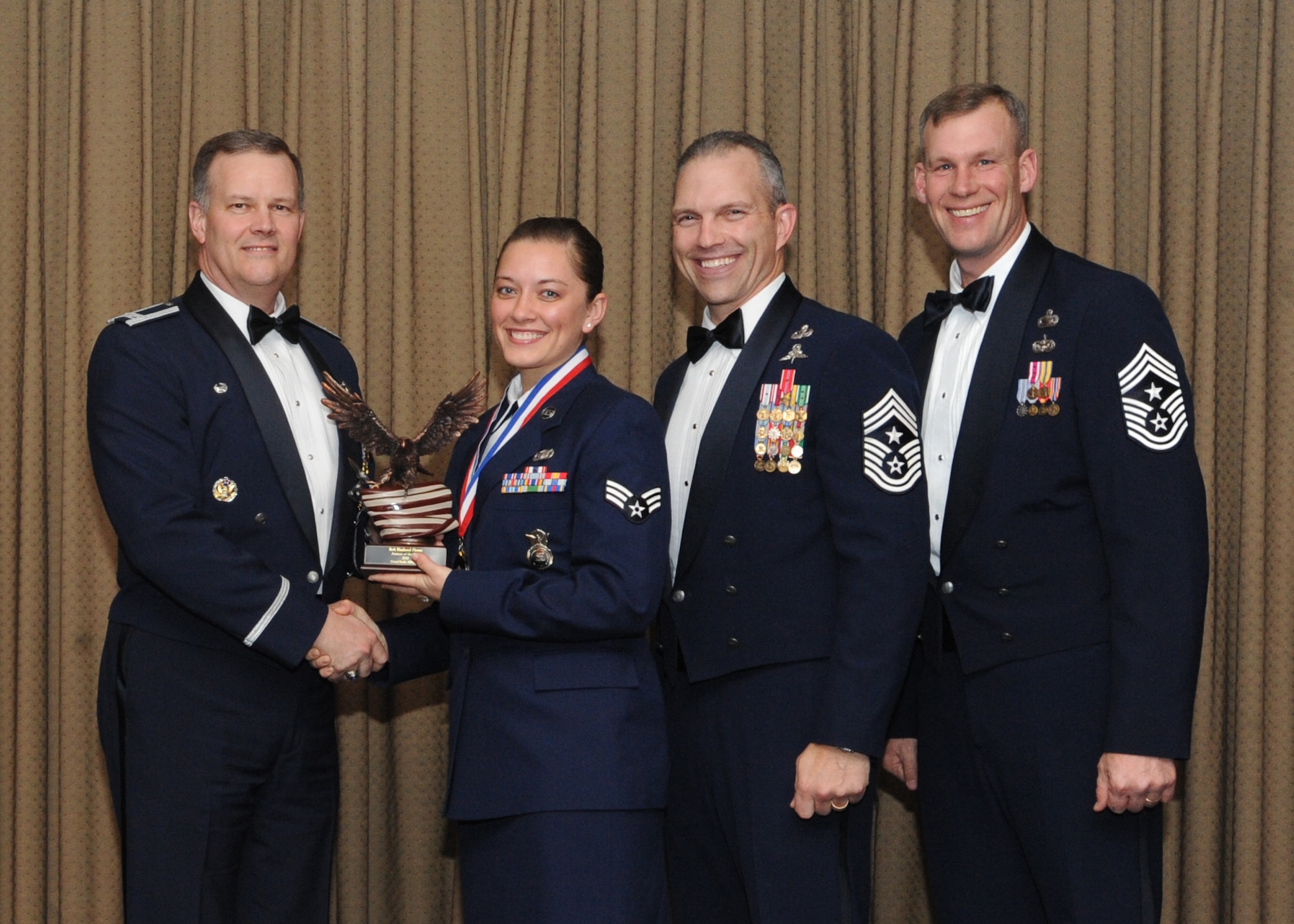 Senior Airman Haaland Flores, 319th Security Forces Squadron, is presented with the 2010 Airman of the Year award for Grand Forks Air Force Base Feb. 4 at the Northern Lights Club. Presenting the award is Col. Don Shaffer, 319th Air Refueling Wing commander, along with Command Chief Master Sgt. Martin Klukas, Air Combat Command, and Command Chief Master Sgt. David Carlson, 319th Air Refueling Wing. (U.S. Air Force photo by Staff Sgt. Suellyn Nuckolls)