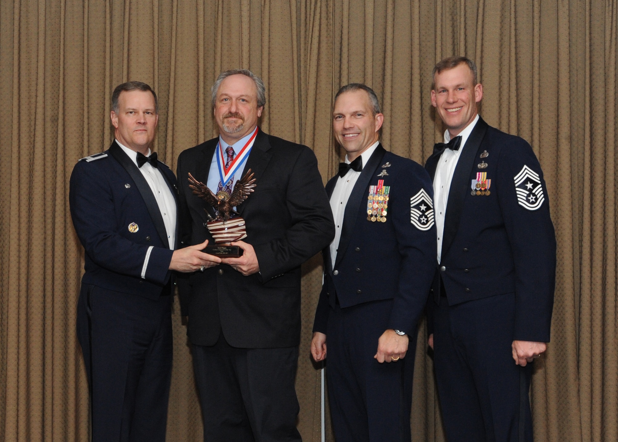 Scott Phipps is presented with the 2010 Category Two Civilian of the Year award for Grand Forks Air Force Base Feb. 4 at the Northern Lights Club. Presenting the award is Col. Don Shaffer, 319th Air Refueling Wing commander, along with Command Chief Master Sgt. Martin Klukas, Air Combat Command, and Command Chief Master Sgt. David Carlson, 319th Air Refueling Wing. (U.S. Air Force photo by Staff Sgt. Suellyn Nuckolls)