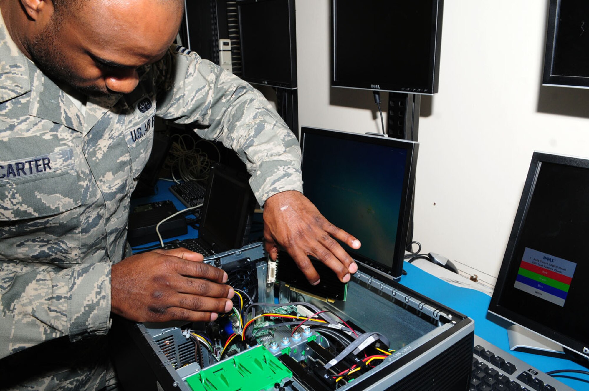 RAF MILDENHALL, England -- Senior Airman Jason Carter, 100th Communications Squadron client service technician, changes out a memory card and adds a video card to a customer's desktop system Feb. 3, 2011, at the 100th CS Client Services Center. In the consolidated workbench area, technicians fix customers computers that for some reason can't be fixed back in their office. (U.S. Air Force photo/Karen Abeyasekere)