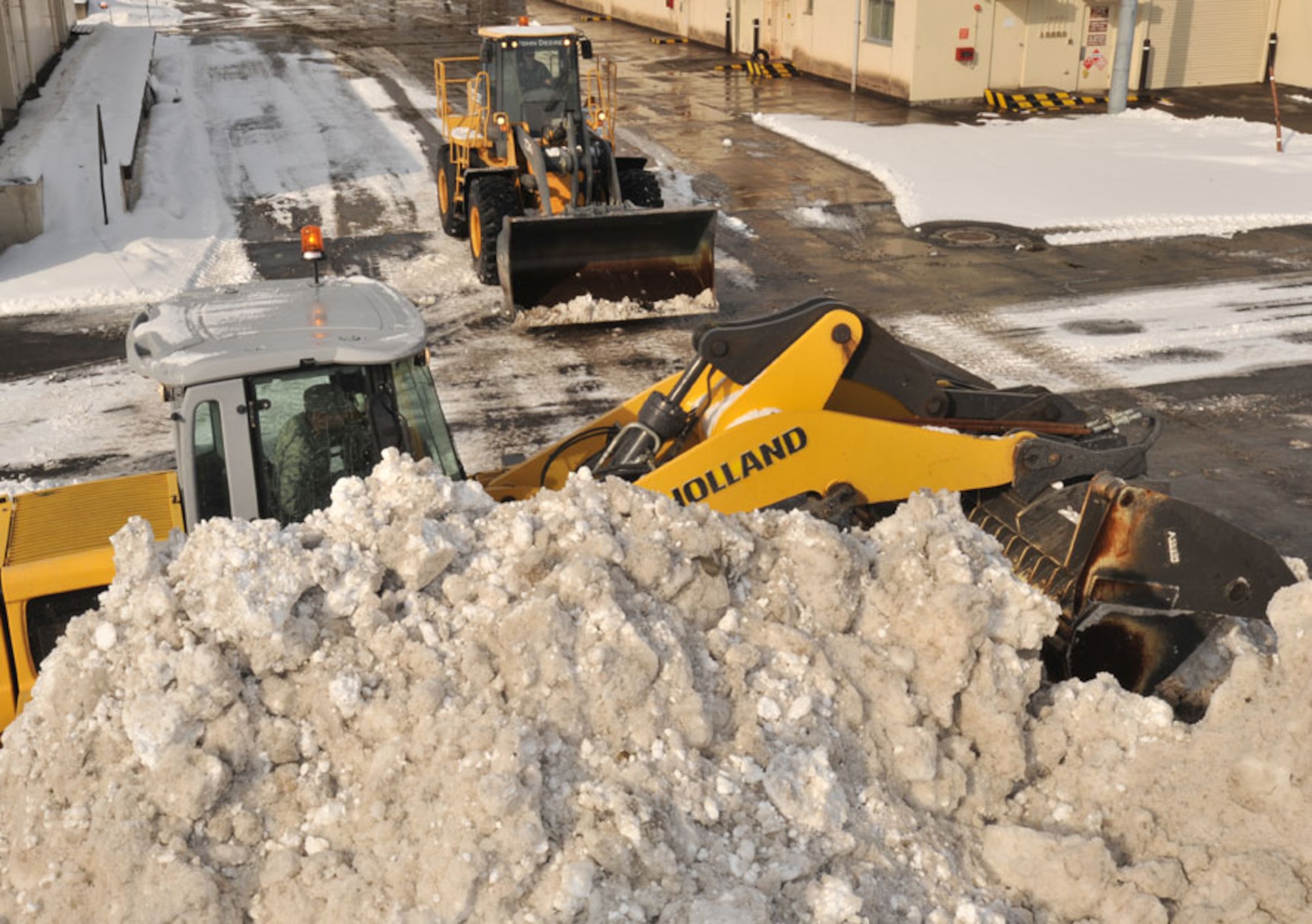 U.S. Air Force Senior Airman Phillip Sechrist, left, and Airman 1st Class Brandon Hotopp, members of the 35th Civil Engineer Squadron snow removal team, work together to clear a parking lot Feb. 8, 2011, at Misawa Air Base, Japan. Last year, the snow removal team cleared approximately 70,000 tons of snow. (U.S. Air Force photo by Airman James B. Bauer/Released)