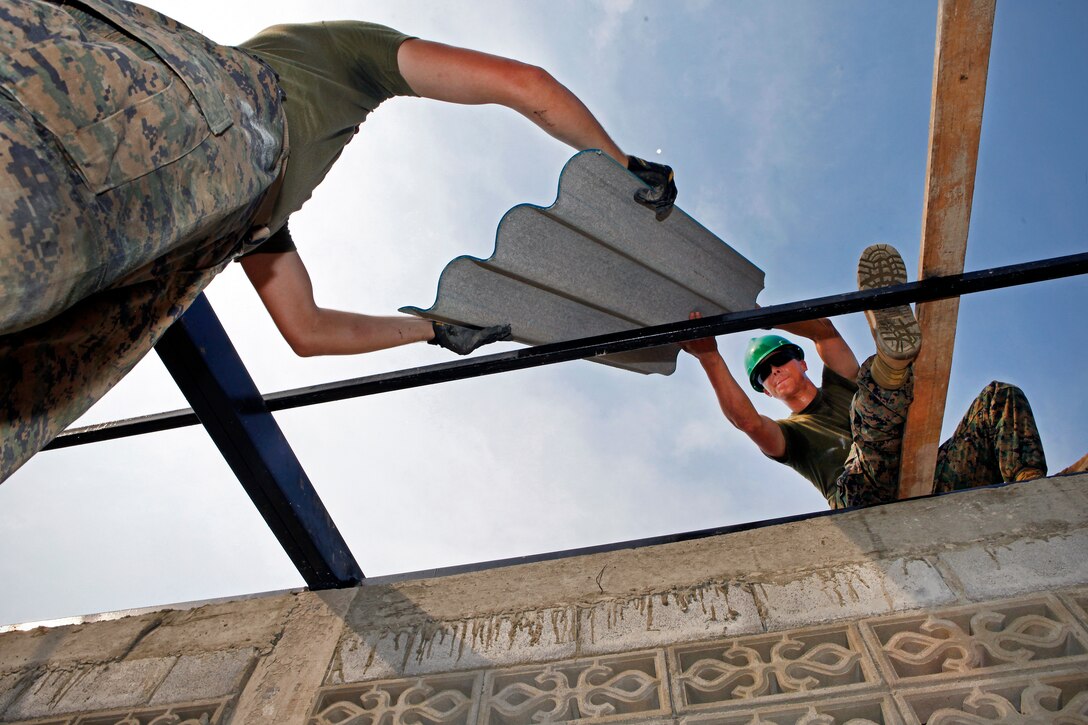 U.S. Marine Corps Lance Cpl. Damian Varnell, left, hands U.S. Marine Corps Staff Sgt. Jon Norris a roof panel as part of a humanitarian and civic assistance program in Thailand's Chanthaburi province, Feb. 3, 2011. The Marines took part in Cobra Gold 2011, a multinational exercise. Varnell and Norris are assigned to Marine Wing Support Squadron 172, Marine Wing Support Group 17, 1st Marine Air Wing. 