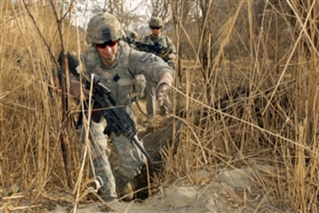 U.S. Army Spc. Nicholas Francioso crosses a small irrigation canal during a patrol in the Arghandab district in Afghanistan's Kandahar province on Jan. 31, 2011.  