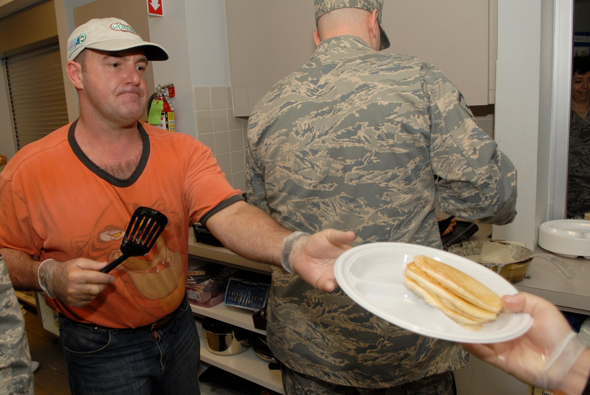 VANDENBERG AIR FORCE BASE, Calif. -- Handing off a pancake plate, Senior Master Sgt. Michael Levingston, the 14th Air Force first sergeant, helps feed a hungry customer during the 1st Sgt.'s Council Pancake Breakfast event at the Airman and Family Readiness Center here Friday, Feb. 4, 2011.  The 1st Sgt.'s Council held the event to raise money for the Vandenberg Food Pantry, which helps the base community.  (U.S. Air Force photo/Senior Airman Andrew Satran) 

 
 
 