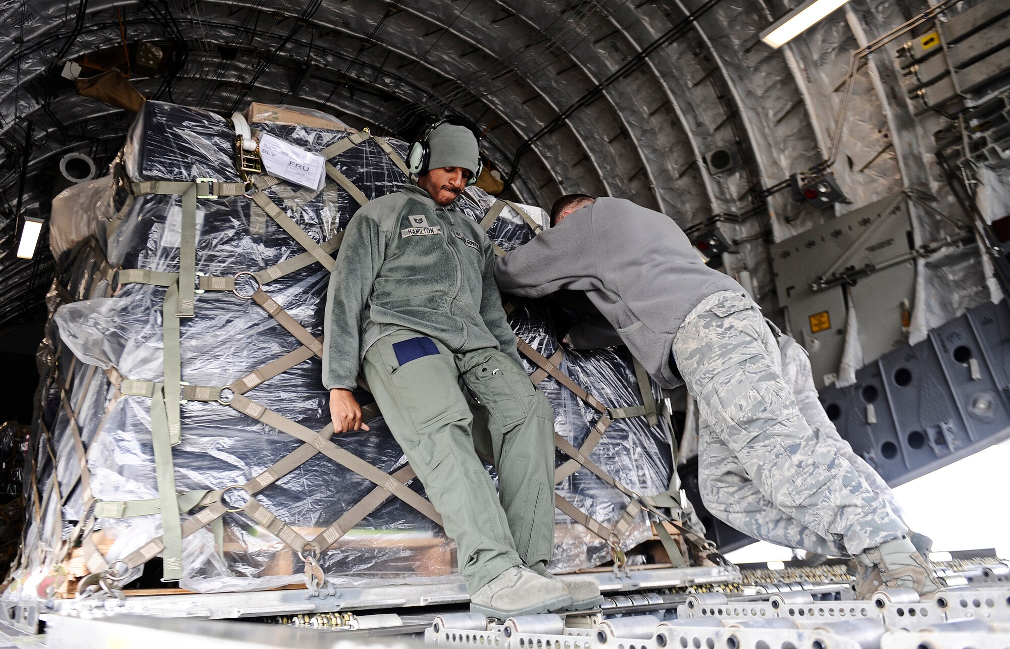 Tech Sgt. Matthew Hamilton helps members of the 375th Logistics Readiness Squadron push a 500-pound pallet onto a C-17 Globemaster III Feb. 7, 2011, at Scott Air Force Base, Ill. Sergeant Hamilton is a loadmaster assigned to the 452nd Air Mobility Wing. (U.S. Air Force photo/ Staff Sgt. Ryan Crane)