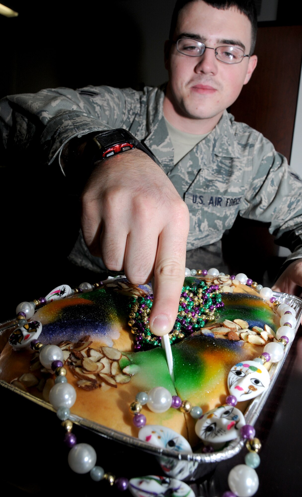 Airman 1st Class Steven Holbrook, a cyber transport student in the 338th Training
Squadron, cuts a slice of king cake. This Mardi Gras tradition is new to Airman Holbrook, who hails from Lincoln Park, Mich.  (U.S. Air Force photo by Kemberly Groue)