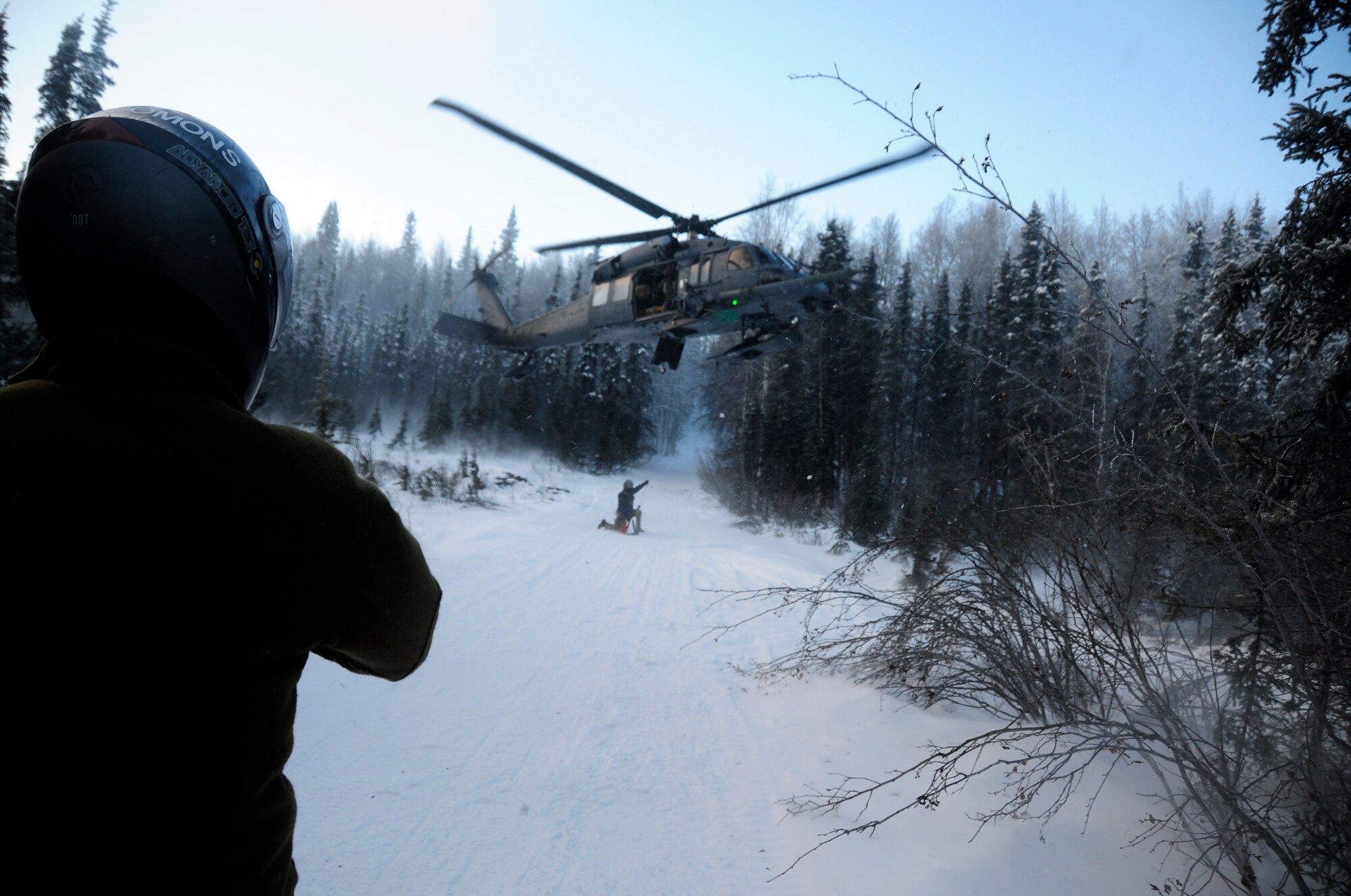 Senior Airman Levi Wood waits as rescue helicopter and aircrew prepare to evacuate him Jan. 26, 2011, Eielson Air Force Base, Alaska.  SERE specialists receiving level-3 and level 5 upgrade training are expected to radio in precise coordinates to make it easier for pilots to find those in need of rescue.  Airman Wood is assigned to Arctic Survival School, Detachment 1, 66th Training Squadron as a SERE specialist.  (U.S. Air Force photo by/Airman 1st Class Yash Rojas)