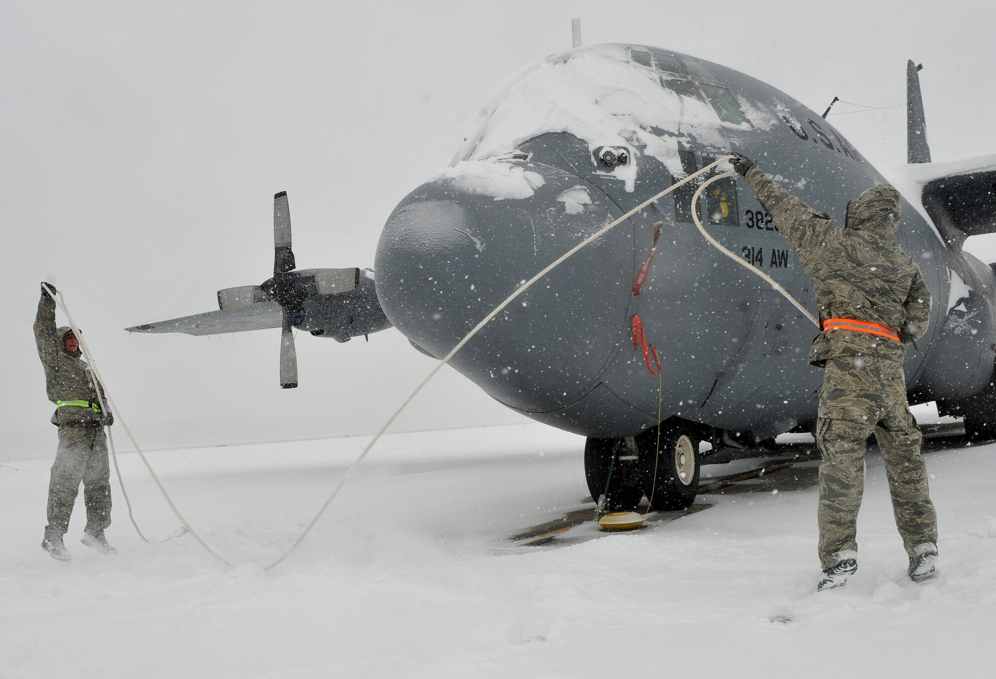 Members of the 19th Aircraft Maintenance Squadron, throw ropes on top of the C-130 Hercules to assist the snow down from the plane on Feb. 9, 2011 at Little Rock Air Force Base, Ark. Maintenance Airmen diligently removed snow from aircraft to minimize the possibility of damage. (U.S. Air Force photo by Senior Airman Gul Crockett)