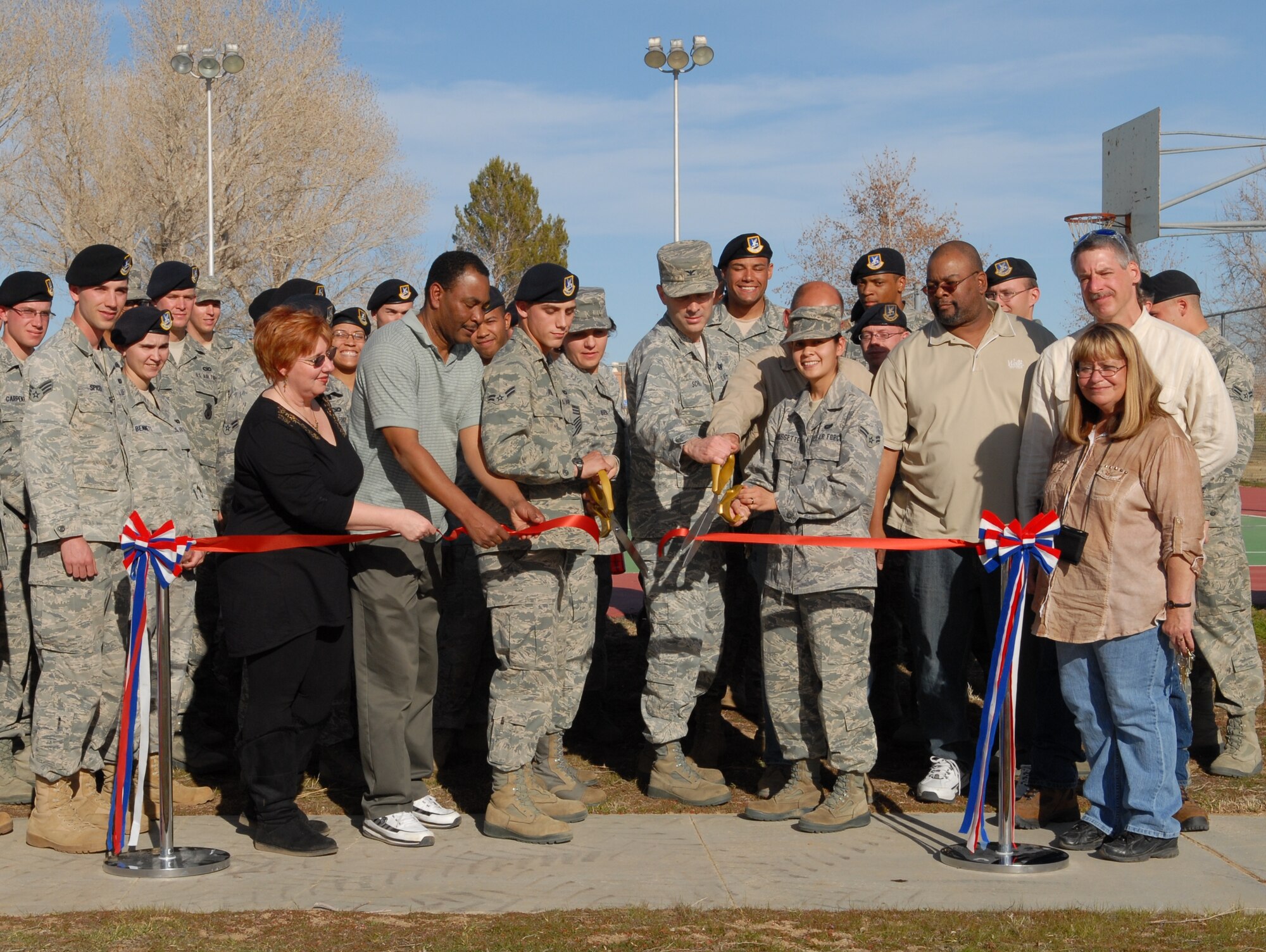 Col. Gregory Schwab, 95th Air Base Wing commander, along with Civil Engineering Division and Edwards dorm residents cut the ribbon symbolizing the reopening of the basketball and volleyball courts behind the Joshua Inn Dining Facility here Feb. 4. Colonel Schwab sent out a survey to Airmen to ask them why they didn’t use the courts. Based on their suggestions, he had the courts cleaned and lights installed around the basketball court. Colonel Schwab said with the upcoming opening of the dining facility these courts will be in an ideal location for the Airmen. (Air Force photo by Senior Airman William A. O’Brien)