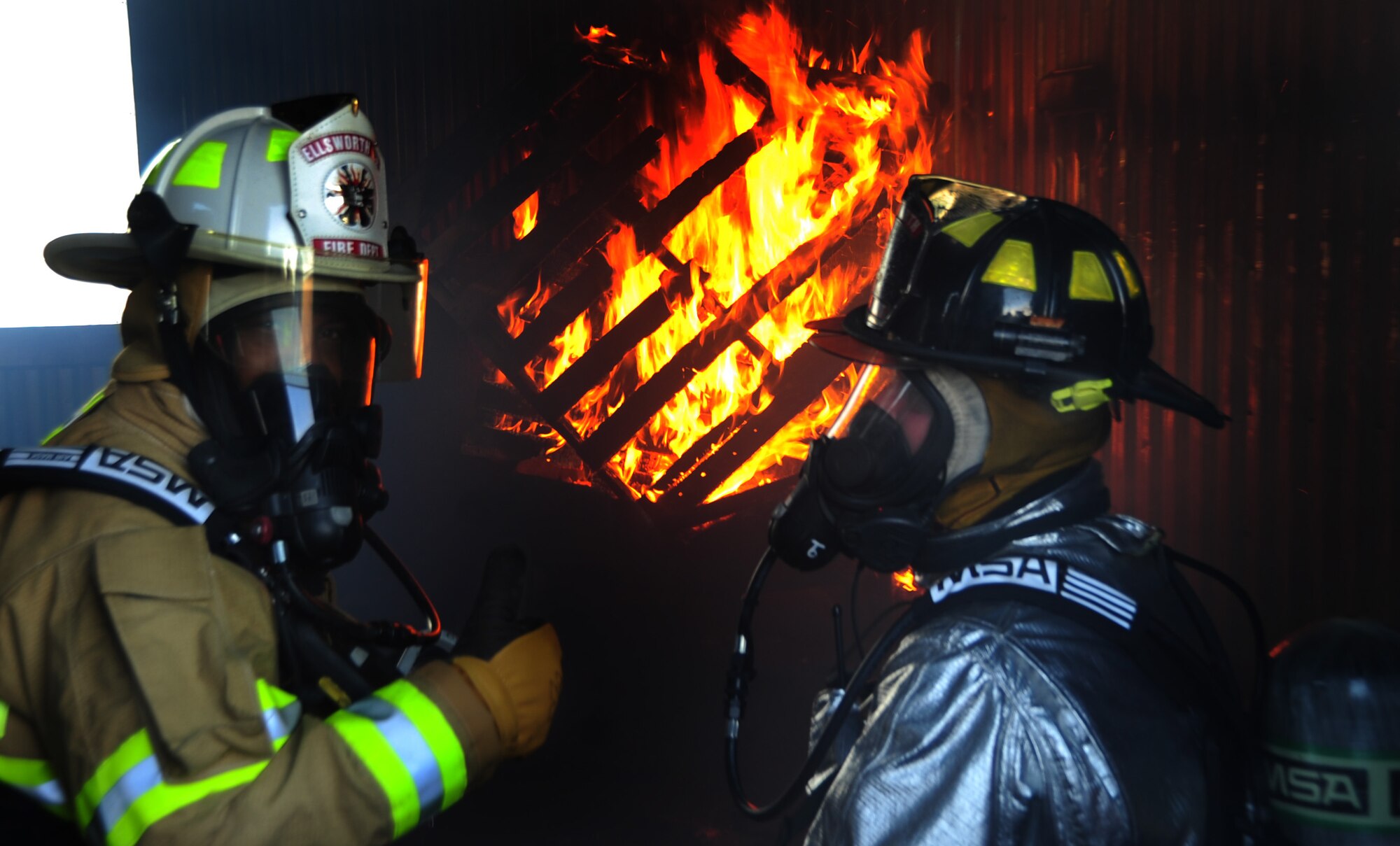 (Left) Col. Trent Edwards, 28th Mission Support Group commander, gives a thumbs-up while training as a firefighter during a controlled indoor fire with Mr. Bill Cina, 28th Civil Engineer Squadron fire truck operator, at Ellsworth Air Force Base, S.D., Jan. 27.  The fire is set inside a training building used solely by the fire department. (U.S. Air Force photo/Senior Airman Anthony Sanchelli)
