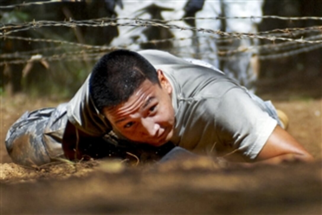 U.S. Air Force Senior Airman Anthony Elizondo low crawls under barbed wire as part of an obstacle course in Wahiawa, Hawaii, on Feb. 1, 2011.  Elizondo is assigned to the 647th Security Forces Squadron, Joint Base Pearl Harbor-Hickam, Hawaii.  