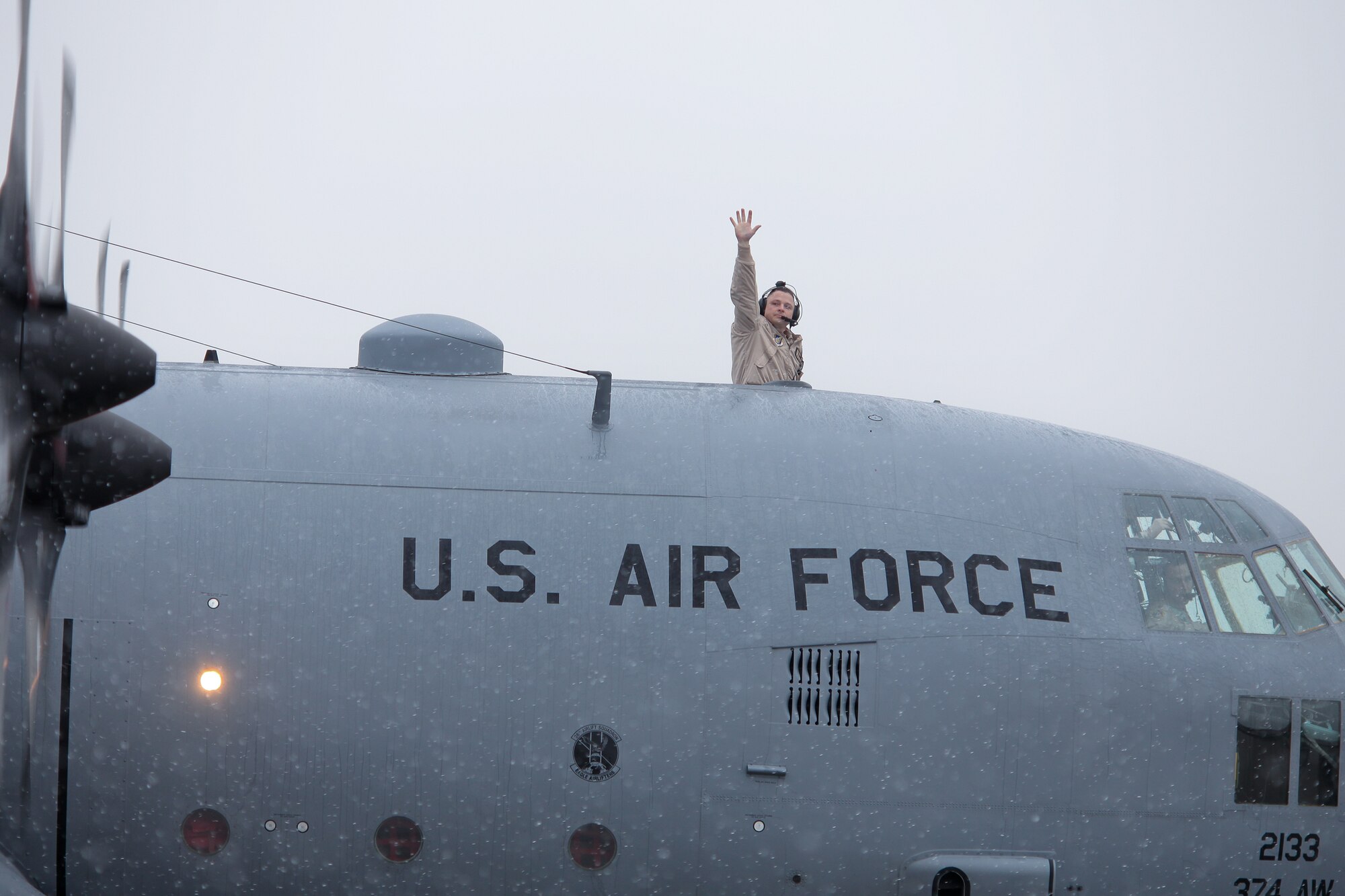 YOKOTA AIR BASE, Japan -- Master Sgt. Thomas Larson, 36th Airlift Squadron flight engineer, waves goodbye from the top hatch of a C-130 Hercules here Feb. 9. Members from the 36th AS, 374th Operations Support Squadron and 374th Logistics Readiness Squadron deployed to Southwest Asia. (U.S. Air Force photo/Osakabe Yasuo)