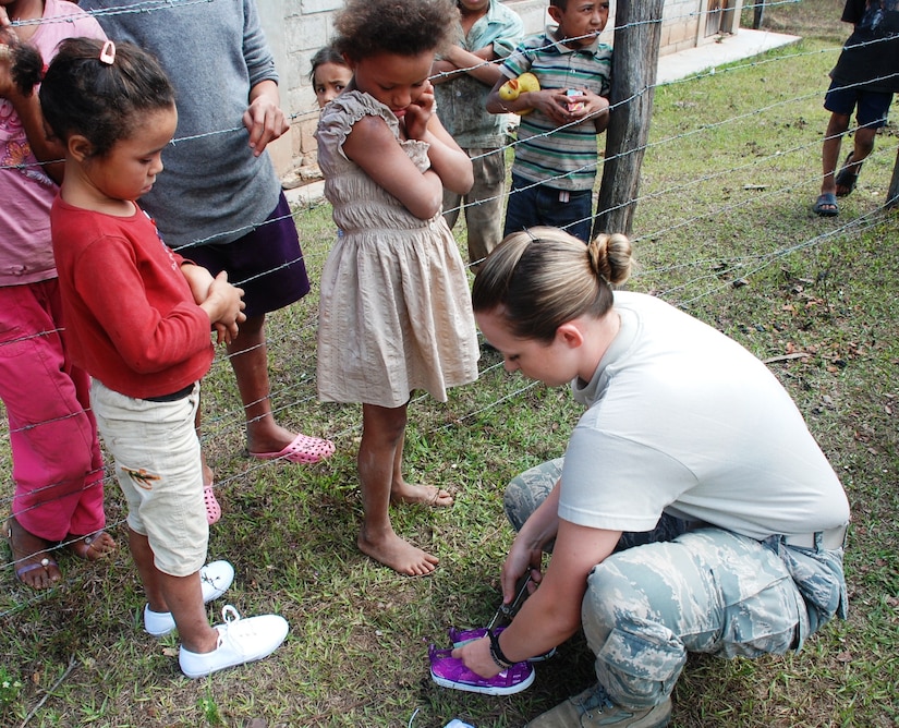 SOTO CANO AIR BASE, Honduras - Airman 1st Class Traci Blakely, Joint Task Force-Bravo Medical Element tecnician, fits a child in Montana de la Flor with a new pair of shoes Jan. 29.  Blakely served on a team of personnel from Joint Task Force-Bravo during a medical readiness training exercise there.  The shoes were donated by the American non-governmental organization Honduras Mission LeMars. (U.S. Air Force photo/Capt. John T. Stamm)