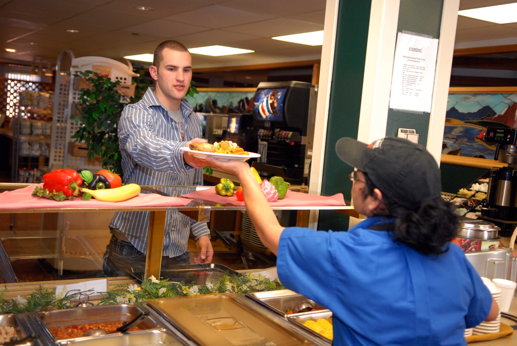 Airman 1st Class Chase Ritter, 90th Civil Engineer Squadron, takes his lunch plate from Susanna Watts, 90th Force Support Squadron at Chadwell Dining Facility on F. E. Warren Air Force Base, Wyo. Jan. 28. (U.S. Air Force photo by R.J. Oriez)