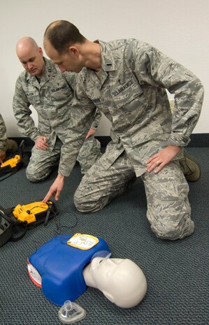 NELLIS AIR FORCE BASE, NEV.-- 1st Lt. Aaron Throne and Capt. James Galyon, 99th Air Base Wing chaplains, simulate using an automated external defibrillator during a heart saver course Feb. 2. The course kicked-off the beginning of AEDs being placed in public areas around the base.  (U.S Air Force photo by Senior Airman Stephanie Rubi)