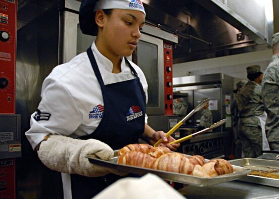 Airman 1st Class Estrella Zapata Miles, a 12th Missile Squadron missile chef, gets ready to prepare spinach-stuffed chicken wrapped in bacon for the judges of the first 2011 Warrior Chef competition.  Their chicken along with baked macaroni and cheese took first place in the competition.  (U.S. Air Force photo/Staff Sgt. Dillon White)