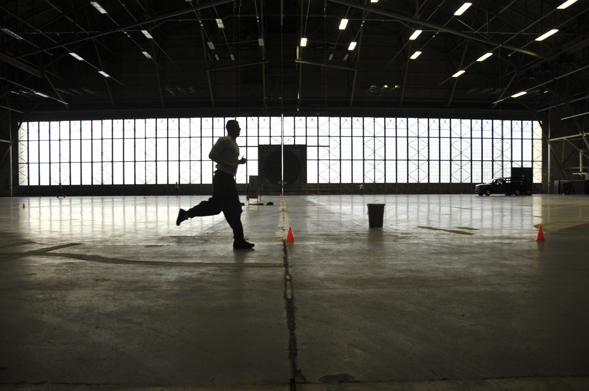 Fairchild Airmen run on a track inside a vacant hangar for a physical training test Feb. 3, 2011. The hangar is vacant because Fairchild's runway is closed for repairs, so the aircraft are located at local airports. Previously, Airmen ran 24 laps on a track inside the base gym to complete the 1.5 mile run. This track is twice the size of the gym track so Airmen run 12 laps to complete the run. (U.S. Air Force Photo/Senior Airman Natasha E. Stannard)