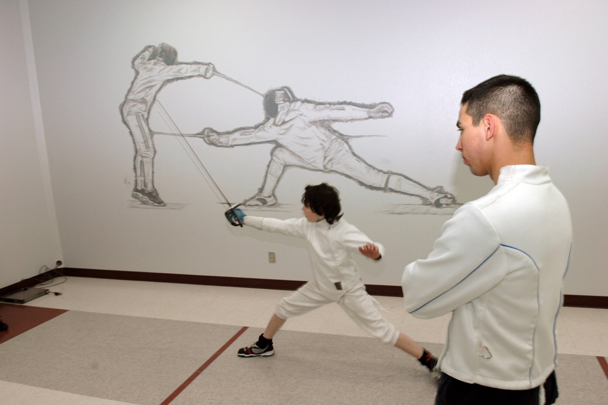 Airman 1st Class Devin Zayas, 673rd Communications Squadron network integration technician, instructs Connor Van Alstrine in proper fencing form Feb. 3, at the Fencing Center of Alaska in Anchorage, Alaska.