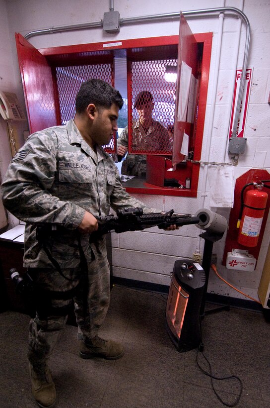 Staff Sgt. Tommy Vallejos, 11th Security Forces Squadron armory shift Non Commissioned Officer, ensures an M-4 rifle with grenade launcher is clear of ammunition prior to issuing it to Airman 1st Class Seth Welty, 11 SFS member, Feb. 7.  (U.S. Air Force photo/Bobby Jones)