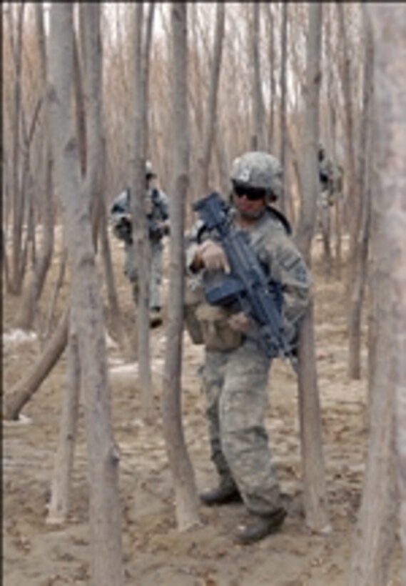 U.S. Army Pfc. Isaias Rodriguez, an infantryman with Charlie Company, 1st Battalion, 66th Armored Regiment, 1st Brigade Combat Team, 4th Infantry Division, squeezes his way through a grove of trees during a foot patrol in Arghandab district, Kandahar province, Afghanistan, on Jan. 31, 2011.  
