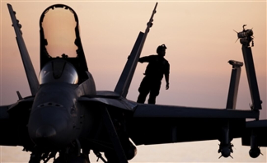 A plane captain performs a pre-flight inspection on an F/A-18C Hornet.