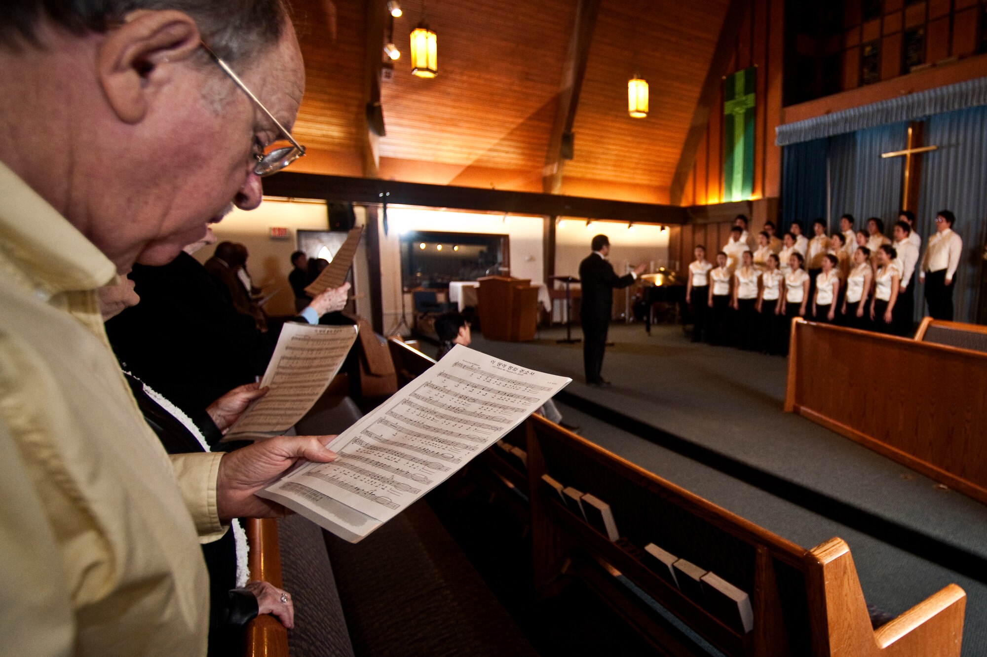 NELLIS AIR FORCE BASE, Nev. --  Chief Master Sgt. Retired Calvin Stickley sings along with The Korean Students Glee Club during a performance at the base chapel Feb. 10. The Korean Students Glee Club is on tour throughout the United States and Canada until Feb. 23, 2011. The Glee Club was established in 1966 and is composed of college students studying music in various universities in the Seoul metropolitan area. (U.S. Air Force photo by Tech. Sgt. Michael R. Holzworth)
