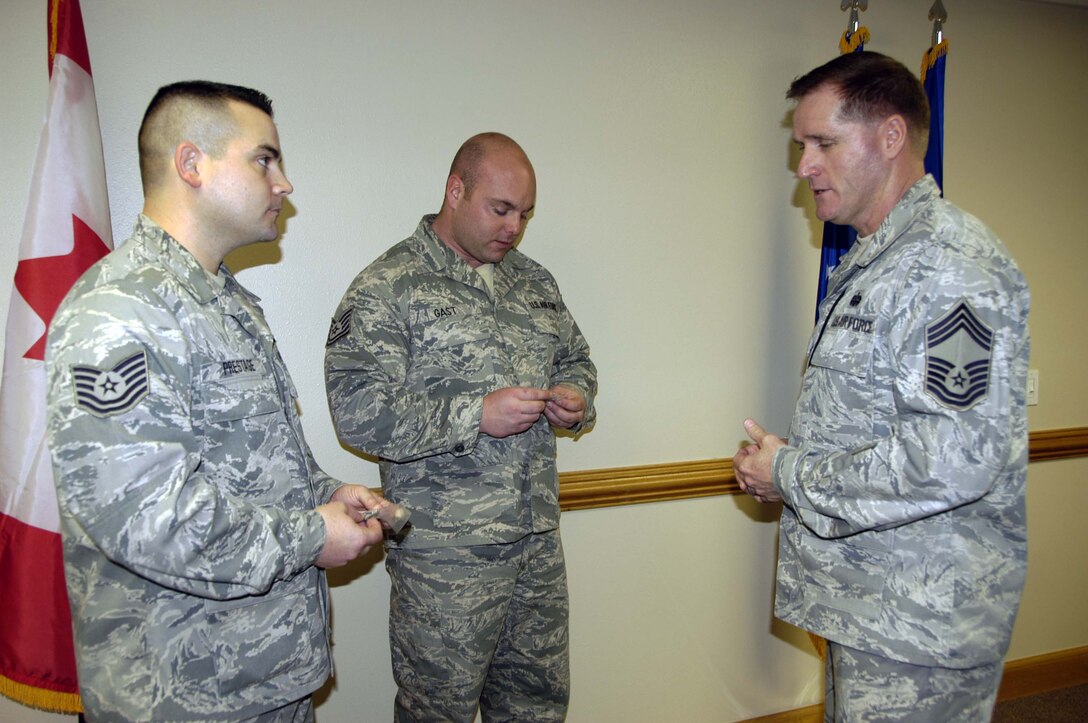 Chief Master Sgt. Carl Collins (right), 702nd Computer Systems Squadron chief enlisted manager, talks with Tech. Sgts. Adam Prestage (left) and Joseph Gast, 702nd CSS, after coining them for emceeing an awards banquet. Chief Collins was the driving force behind a round of mock boards held for the benefit of 1st Air Force (Air Forces Northern) enlisted Airmen. Sergeant Prestage was one of the Airmen who participated in the boards. (U.S. Air Force photo/Angela Pope)