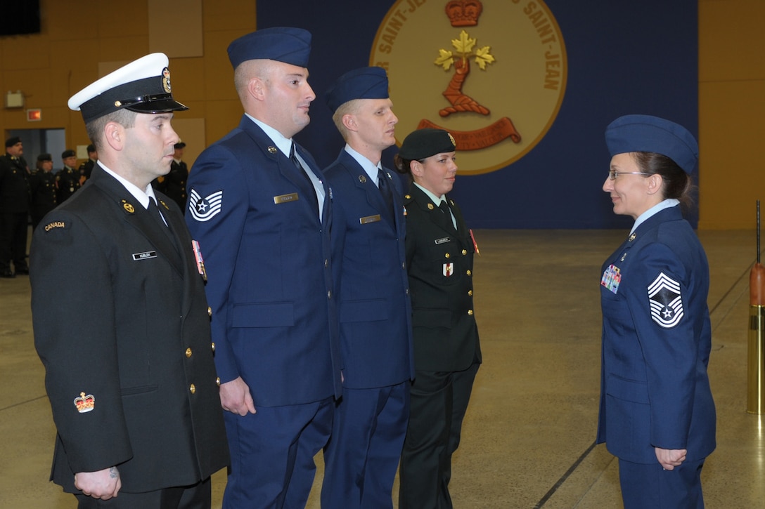 U.S. Air Force Tech. Sgts. Clifford Fallico (second from left), Air Forces Northern intelligence, surveillance and reconnaissance planner, and Robert Carnall, 702nd Computer Support Squadron system administrator (third from left), stand before Chief Master Sgt. Angela Abshire (right), director of standards at the Noncommissioned Member Professional Development Center, at the graduation ceremony where they both earned the “Comradeship Award” from the Canadian Intermediate Leadership Program, Canadian Forces College, Noncommissioned Member Professional Development Center, St. Jean Sur Richlieu in Quebec, Canada.  Only four of 120 students received the peer-voted award. (Photo by Mr. Christian Jaques)