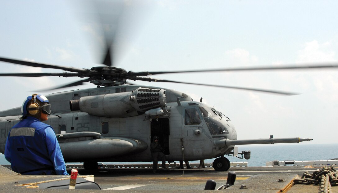 Seaman Skye Kelley waits to remove chocks and chains from a CH-53E Sea Stallion helicopter on the flight deck of the forward-deployed amphibious assault ship USS Essex (LHD 2).