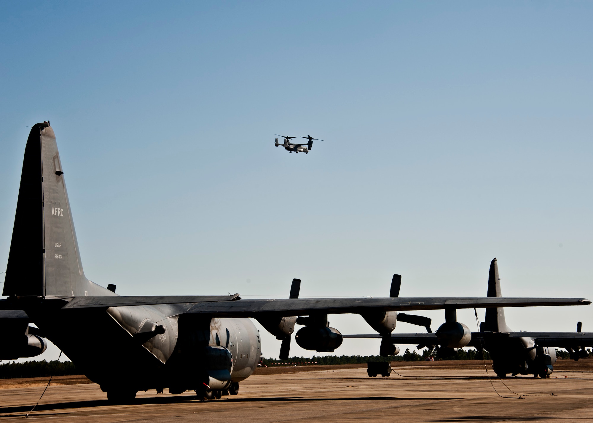 A CV-22 Osprey from the 413th Flight Test Squadron flies overhead as the 919th Special Operations Wing MC-130E Talons wait to be launched.  Duke Field’s flightline is busy again after an eight-month construction project.  (U.S. Air Force photo/Tech. Sgt. Samuel King Jr.)
