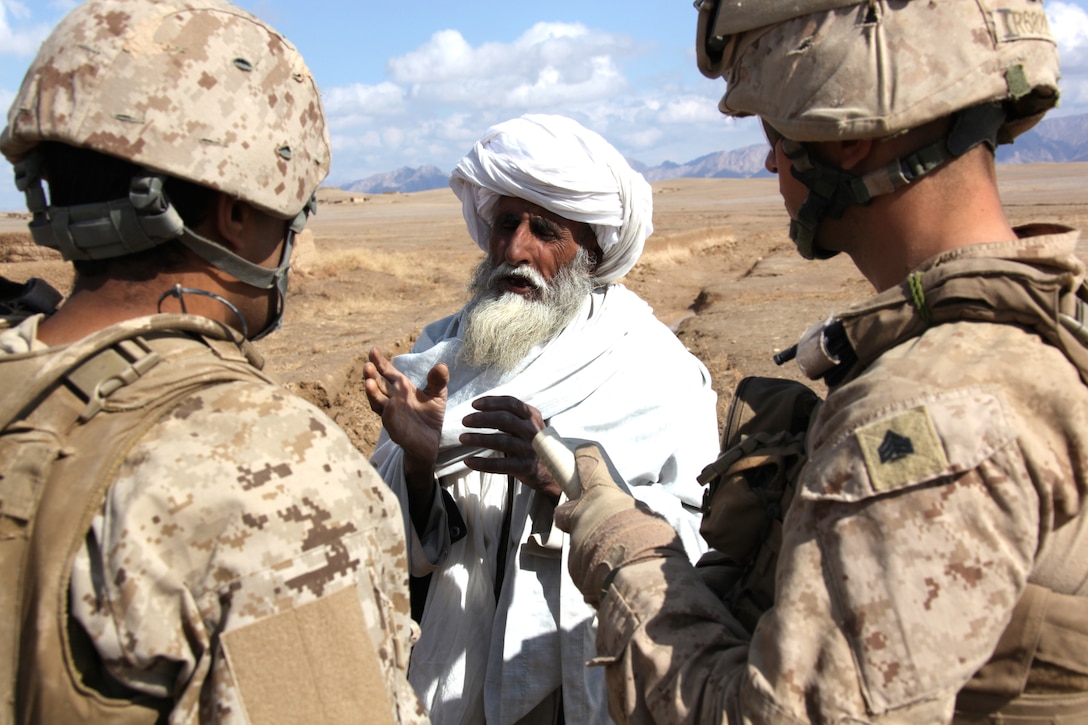 U.S. Marine Corps Sgt. Erik Rasmussen (right), a squad leader with Company I, Battalion Landing Team 3/8, 26th Marine Expeditionary Unit, Regimental Combat Team 8, speaks to a local Afghan through an interpreter to offer assistance following three days of heavy rain at Turah Shah Ghundey, Helmand province, Afghanistan, Feb. 13, 2011. Elements of 26th Marine Expeditionary Unit deployed to Afghanistan to provide regional security in Helmand province in support of the International Security Assistance Force. (U.S. Marine Corps photo by Gunnery Sergeant Bryce Piper/Released)::r::::n::