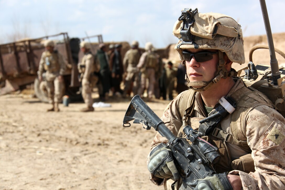 U.S. Marine Corps Lance Cpl. Cody Schneider, a rifleman, stands guard as fellow Marines and interpreters with Company I, Battalion Landing Team 3/8, 26th Marine Expeditionary Unit, Regimental Combat Team 8, speak to Afghans to offer assistance following three days of heavy rain at Turah Shah Ghundey, Helmand province, Afghanistan, Feb. 13, 2011. Elements of 26th Marine Expeditionary Unit deployed to Afghanistan to provide regional security in Helmand province in support of the International Security Assistance Force.