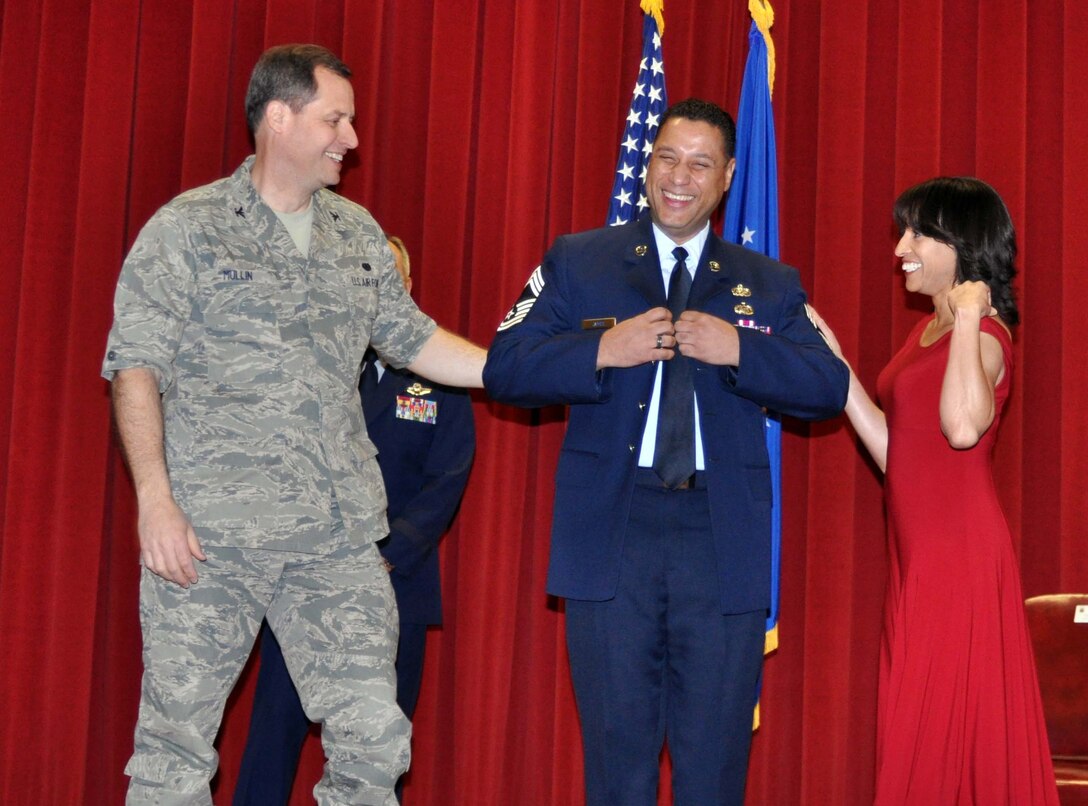 Newly promoted Chief Master Sgt. Mark D. James puts on his new stripes with assistance from his fiance, Simone Lewis, and Col. Samuel Mullin, February 13, 2011.  (U.S. Air Force photo/Master Sgt. Linda Welz)