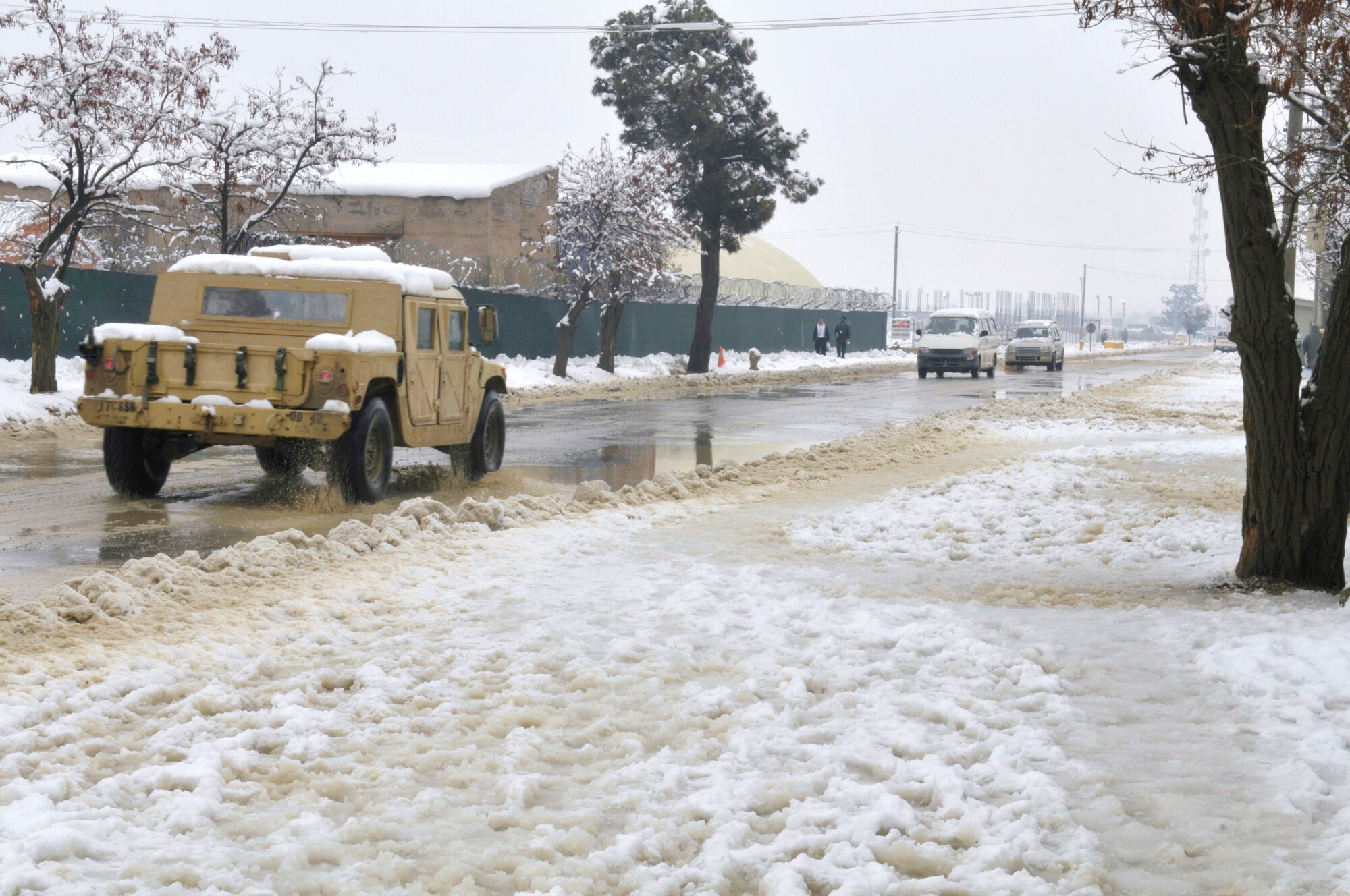 Colder temperatures and snow has become the scene as vehicles pass down Disney Drive on Bagram Airfield, Afghanistan, February 12, 2011. Airmen deployed to the airfield have seen snow continuously fall for the past two days, but it hasn't dampened their spirits. (Air Force photo by Tech. Sgt. Michael Voss)