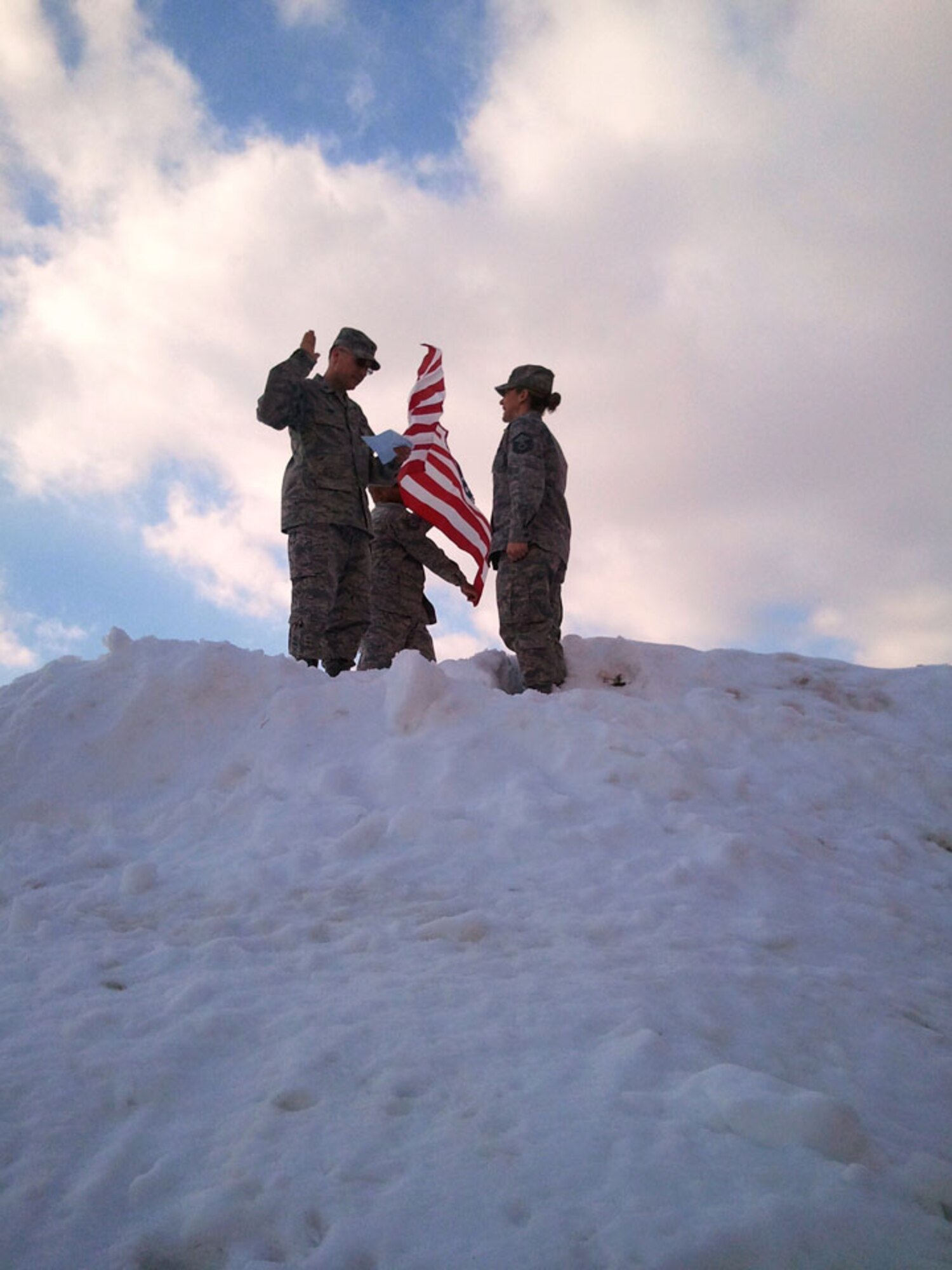 Master Sgt. Careyann Patterson, 58th Aerial Port Squadron takes the reenlistment oath from Lt. Col. Rodney Furr, 58th Aerial Port Squadron on top of a huge snowbank outside of the Hangar. (US Air Force photo)