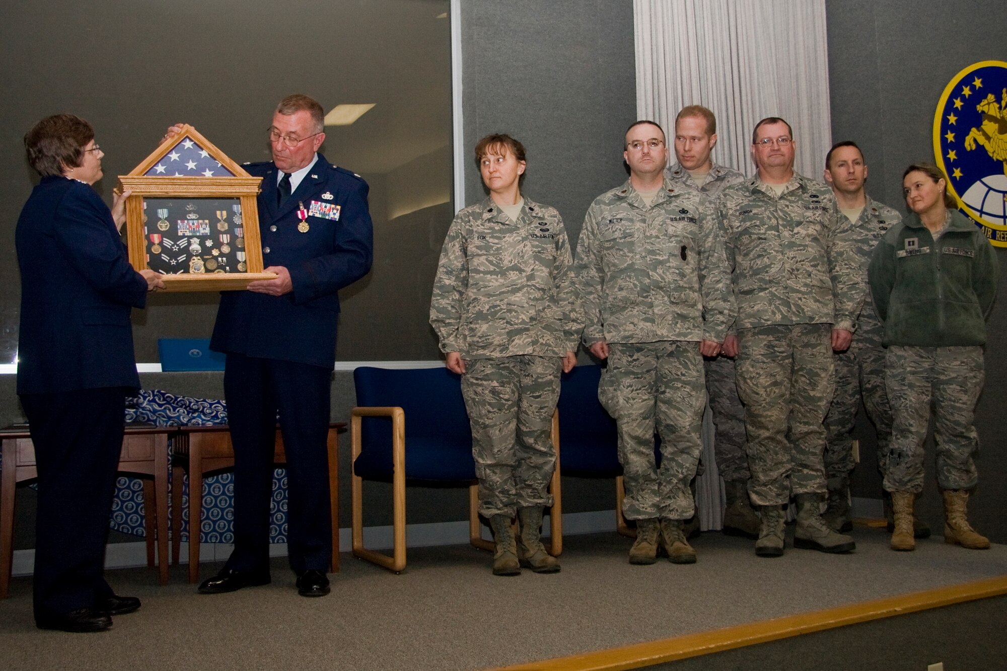 GRISSOM AIR RESERVE BASE, Ind. -- Col. Betty Bowen presents Lt. Col. Phil Shott with a shadow box during his retirement ceremony here recently as squadron commanders, past and present, from the 434th Mission Support Group watch. Colonel Shott retired as the 434th MSG deputy commander, and Colonel Bowen is the group?s commander. Squadron commanders, from left, are Lt. Col. Becky Fox, Maj. Christopher Witter, Maj. Paul Brenner, Lt. Col. Bryan Runion, Maj. Michael Schaefer and Capt. Amanda Owens.   (U.S. Air Force photo/Tech. Sgt. Mark R. W. Orders-Woempner)
