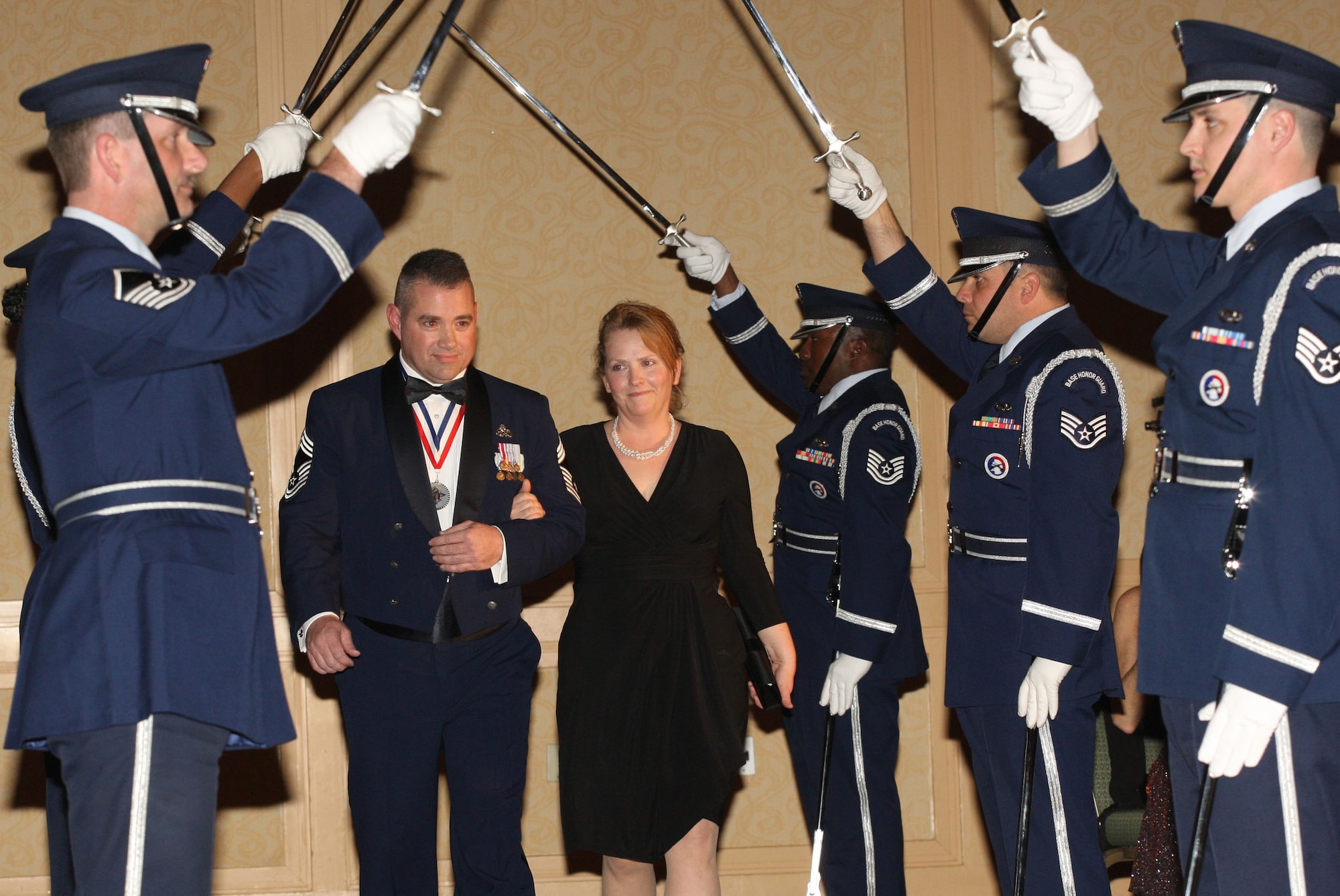 Chief Master Sgt. Don Sharp, Superintendent of the 94th Aircraft Maintenance Squadron, and his wife, Lisa make their way through a Saber Team, from members of the 94th Airlift Wing Honor Guard beginning the evenings event Feb 5. (U.S. Air Force Photo/Don Peek)