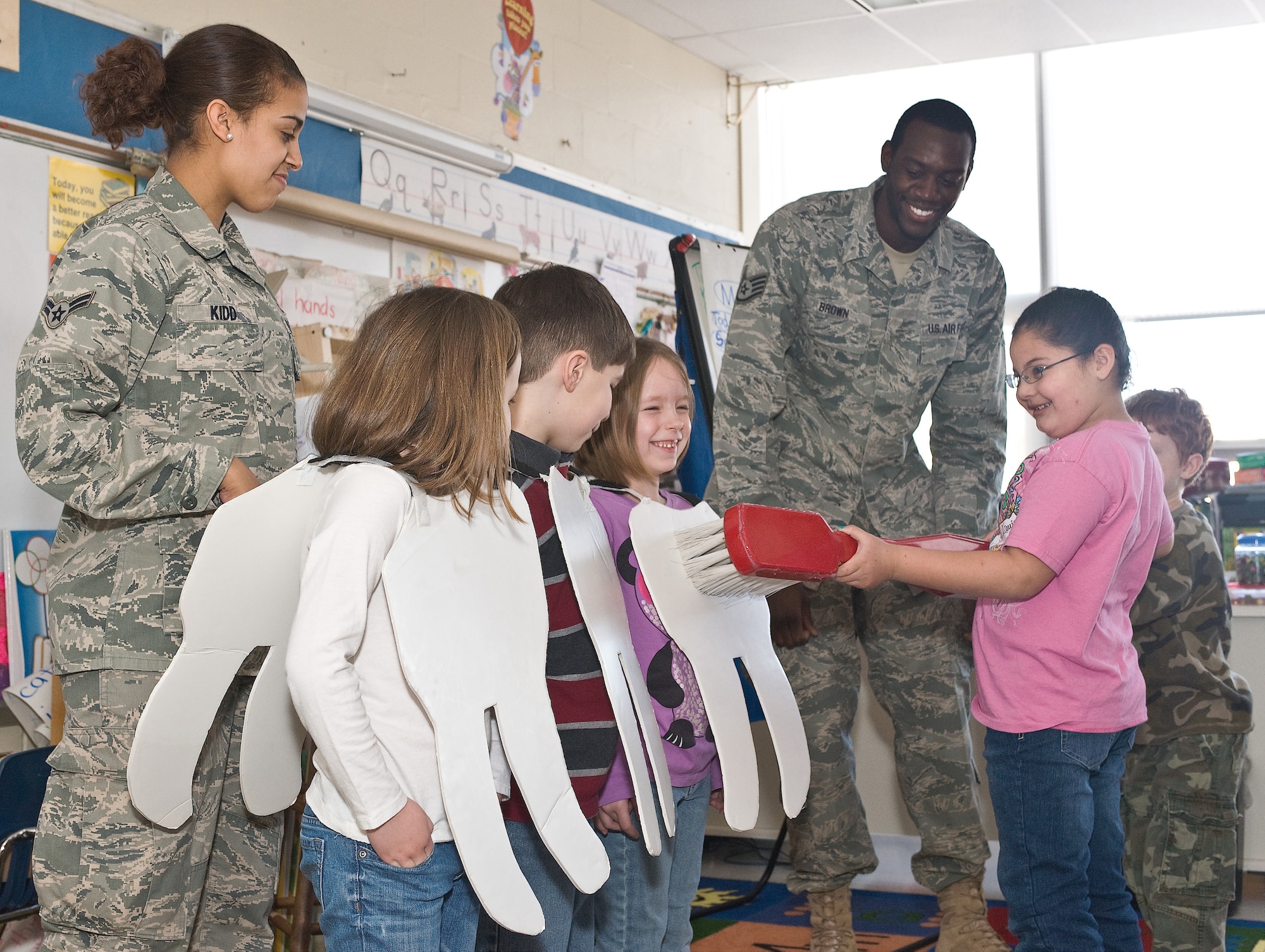 Airman 1st Class Dejon Kidd and Staff Sgt. James Brown, both assigned to the 436th Dental Squadron, teach Sue Taraila's students the proper way to brush teeth with a reenactment as part of Children Dental Health Month, Feb. 10, 2011, at Dover Air Force Base, Del. (U.S. Air Force photo/Roland Balik)