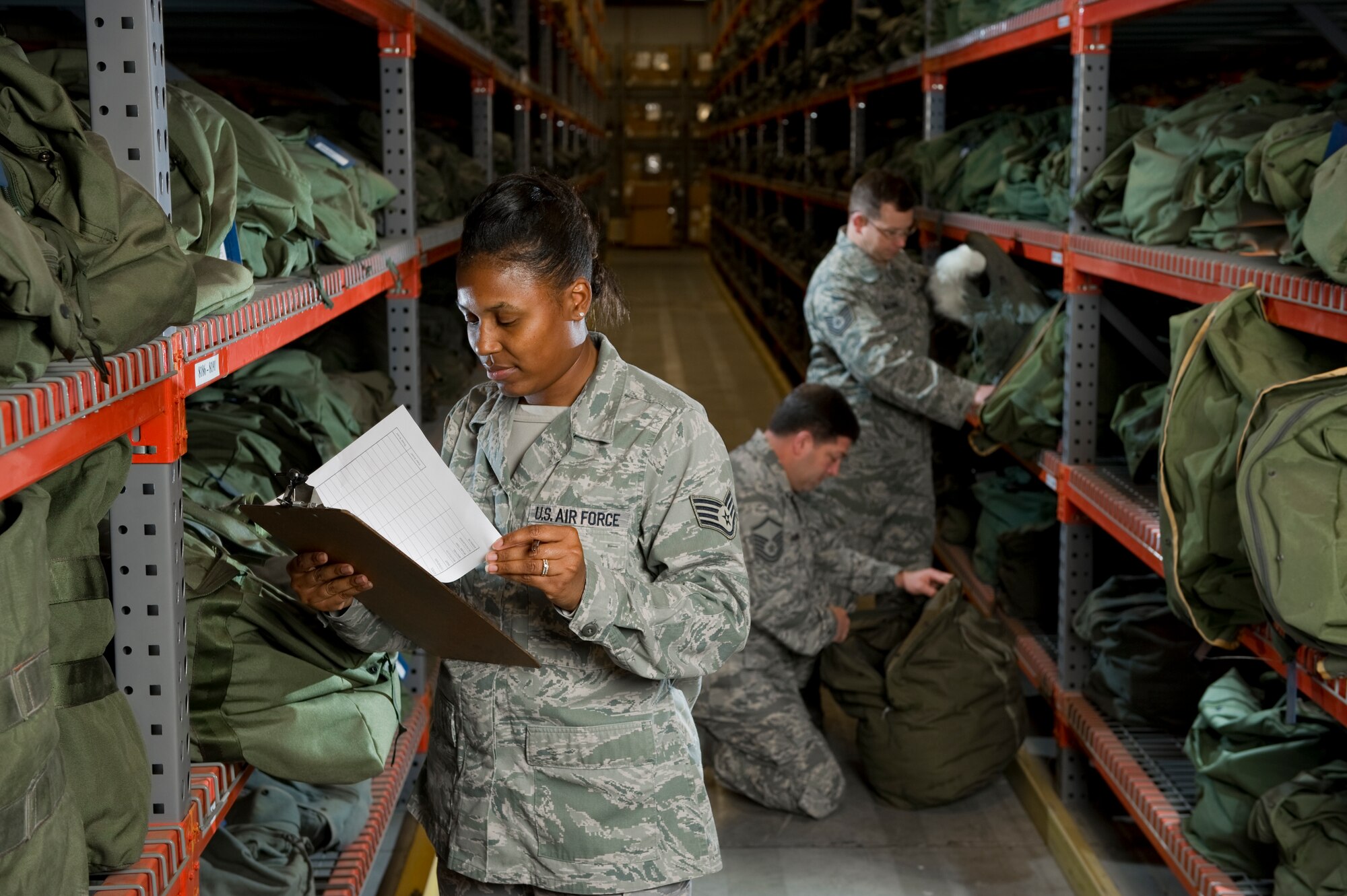 Stacy Pearsall photographed Staff Sgt. Tiffany Horry (front), Master Sgt. Steve Sherrill (kneeling), and Tech Sgt. Kris Williams (standing in back) in the Logistical Readiness Squadron’s mobility warehouse.  (Courtesy Photo by Stacy Pearsall)