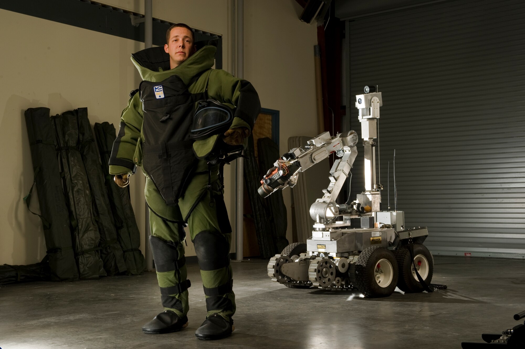 Stacy Pearsall photographed Staff Sgt. Ryan Dehlinger, a 315th Airlift Wing explosive ordinance disposal technician, wears his protective gear in front of a remotely operated EOD unit. (Courtesy Photo by Stacy Pearsall)