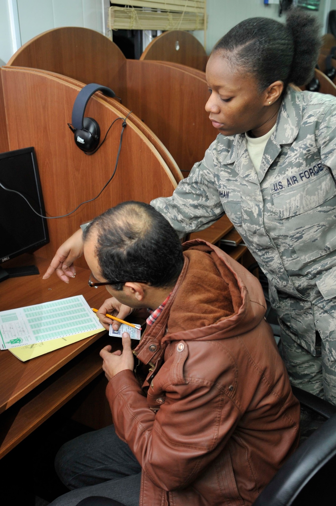 BAGHDAD, Iraq – U.S. Air Force Tech. Sgt. Fatema Tahan, Iraq Security Assistance Mission English Language Program test administrator, helps an Iraqi Air Force officer fill out the administrative portion of the American Language Course Placement Test answer sheet at Forward Operating Base Union III, International Zone, here Feb. 6. (U.S. Air Force photo by Senior Master Sgt. Larry Schneck/Released)
